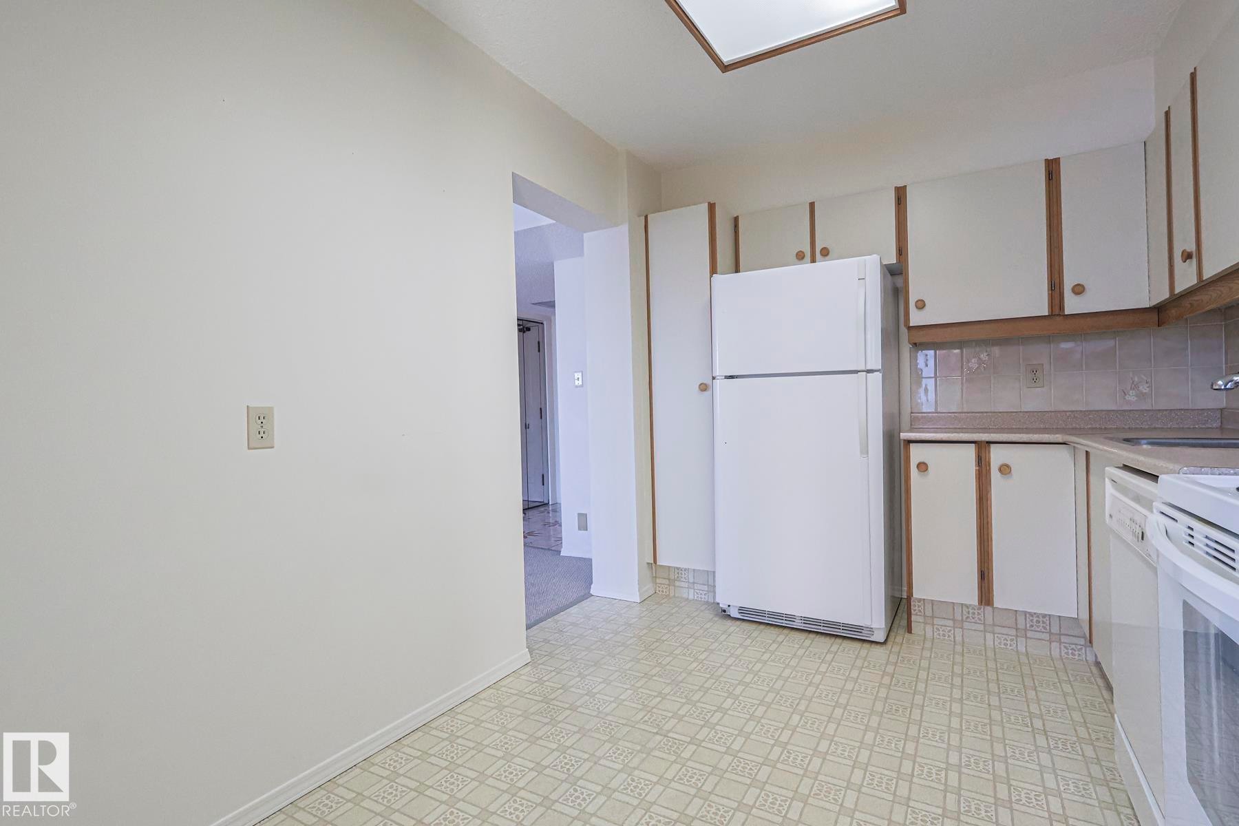 Kitchen featuring white appliances, white cabinetry, light flooring, light countertops, and backsplash - 302 8340 Jasper Avenue Nw, Edmonton, AB - Indoor Photo Showing Kitchen