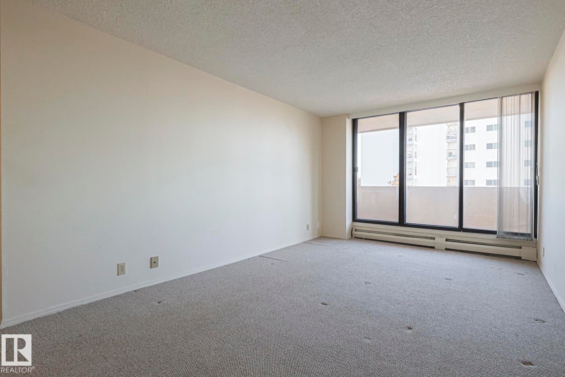 Spare room with baseboard heating, a textured ceiling, and carpet - 302 8340 Jasper Avenue Nw, Edmonton, AB - Indoor Photo Showing Other Room