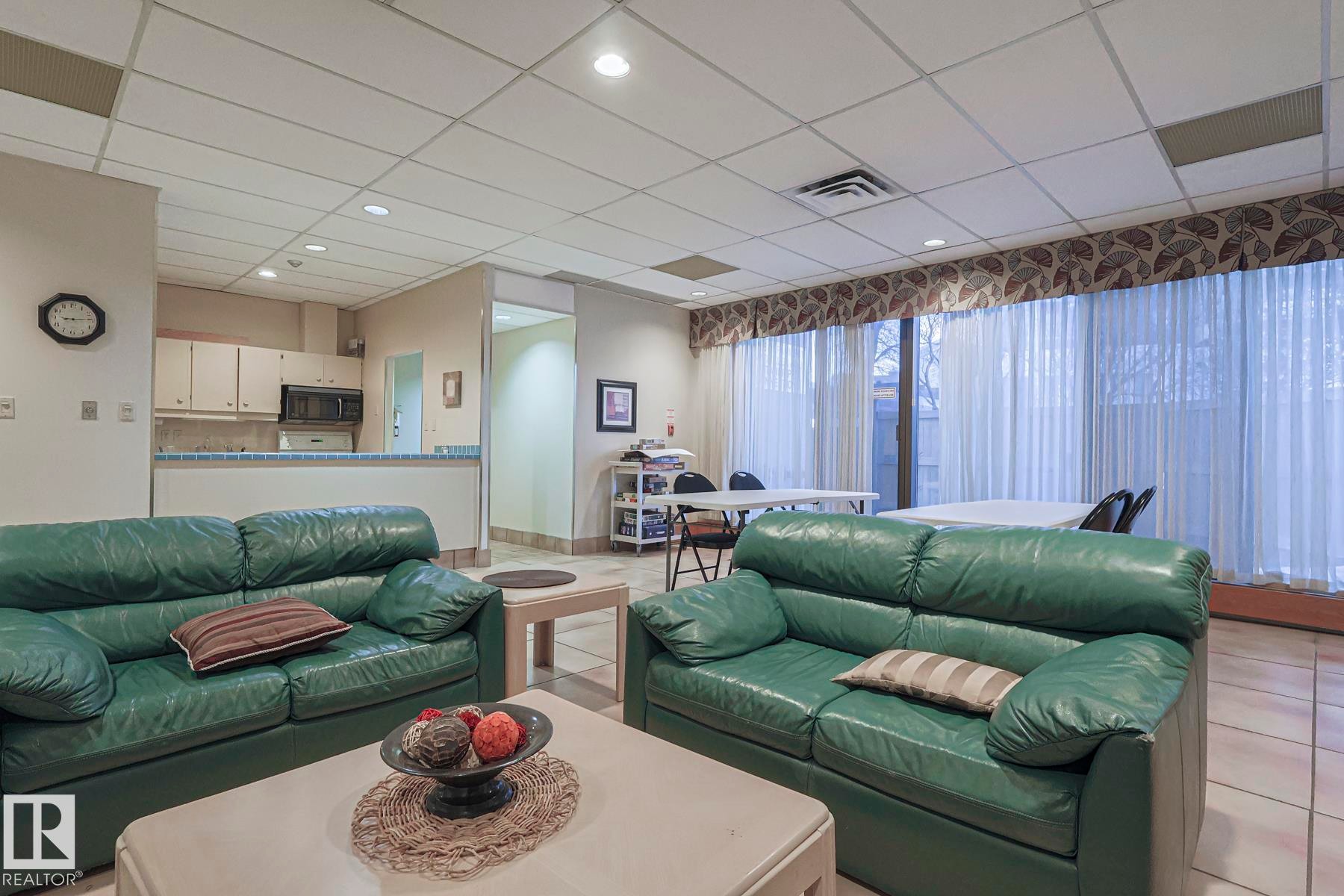 Living area with a paneled ceiling and light tile patterned flooring - 302 8340 Jasper Avenue Nw, Edmonton, AB - Indoor Photo Showing Living Room