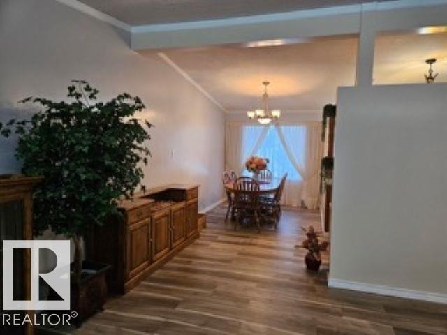 Dining area featuring dark wood-style flooring, a chandelier, ornamental molding, and beamed ceiling - 4910 53 Avenue, Willingdon, AB