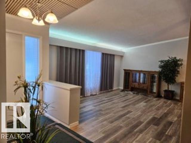 Unfurnished living room with dark wood-type flooring and a chandelier - 4910 53 Avenue, Willingdon, AB