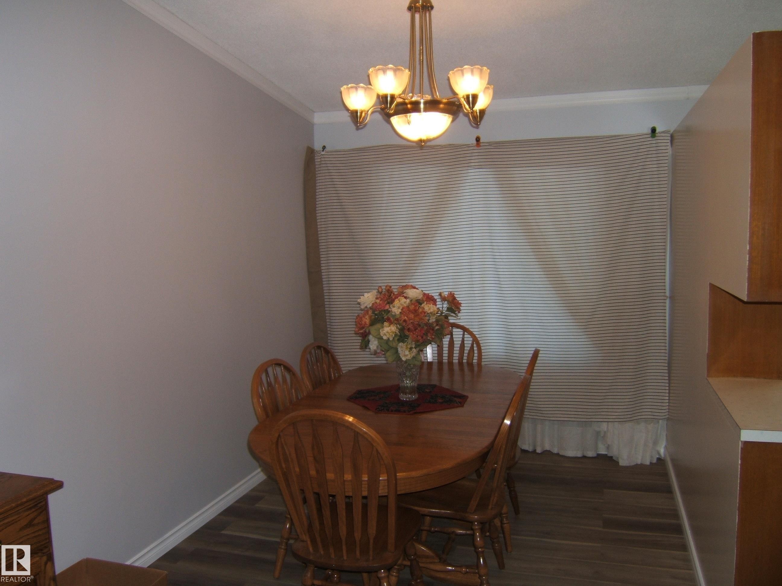 Dining room featuring dark wood finished floors, ornamental molding, and a chandelier - 4910 53 Avenue, Willingdon, AB