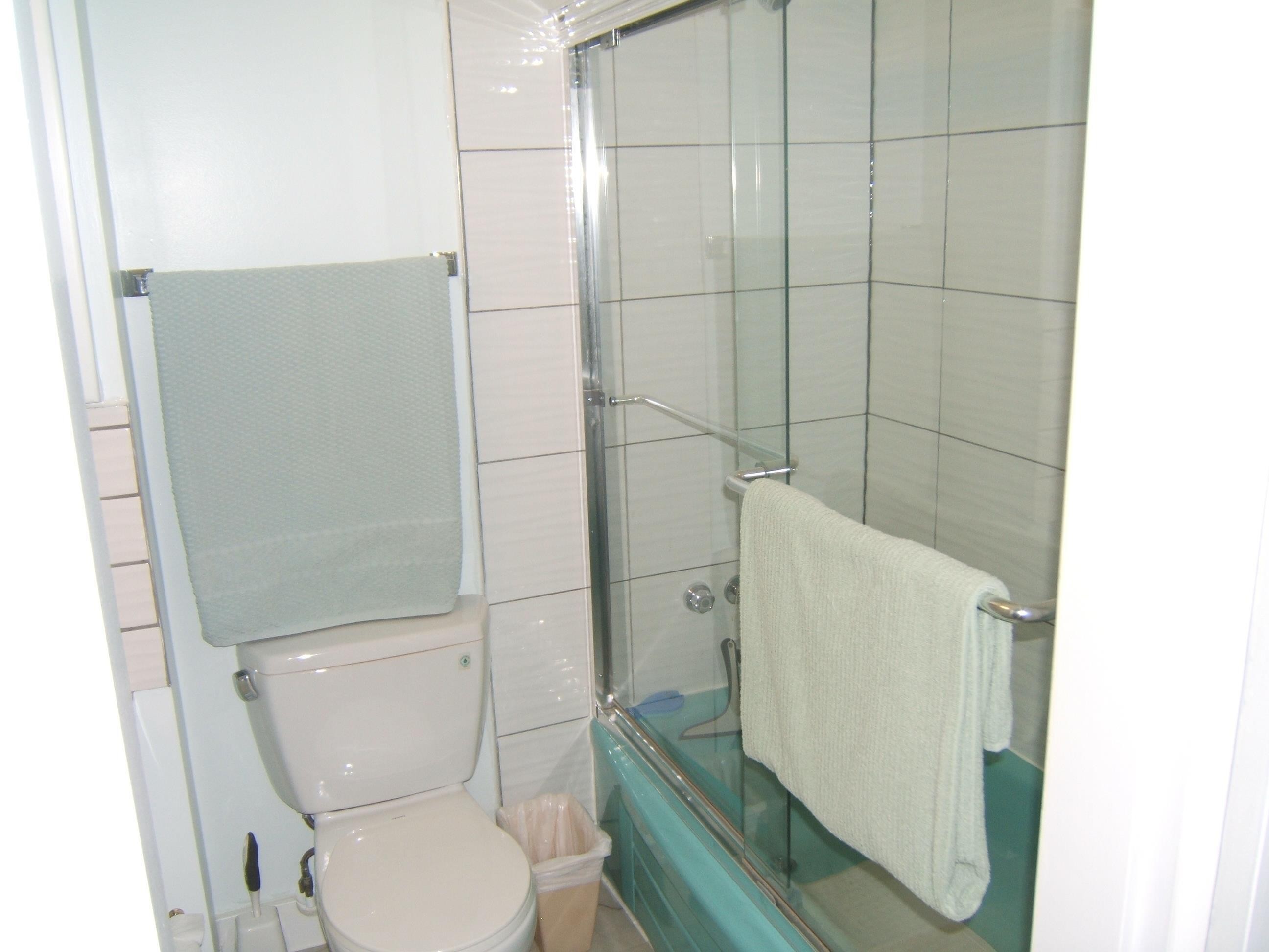 Full bathroom featuring shower / bath combination with glass door and toilet - 4910 53 Avenue, Willingdon, AB