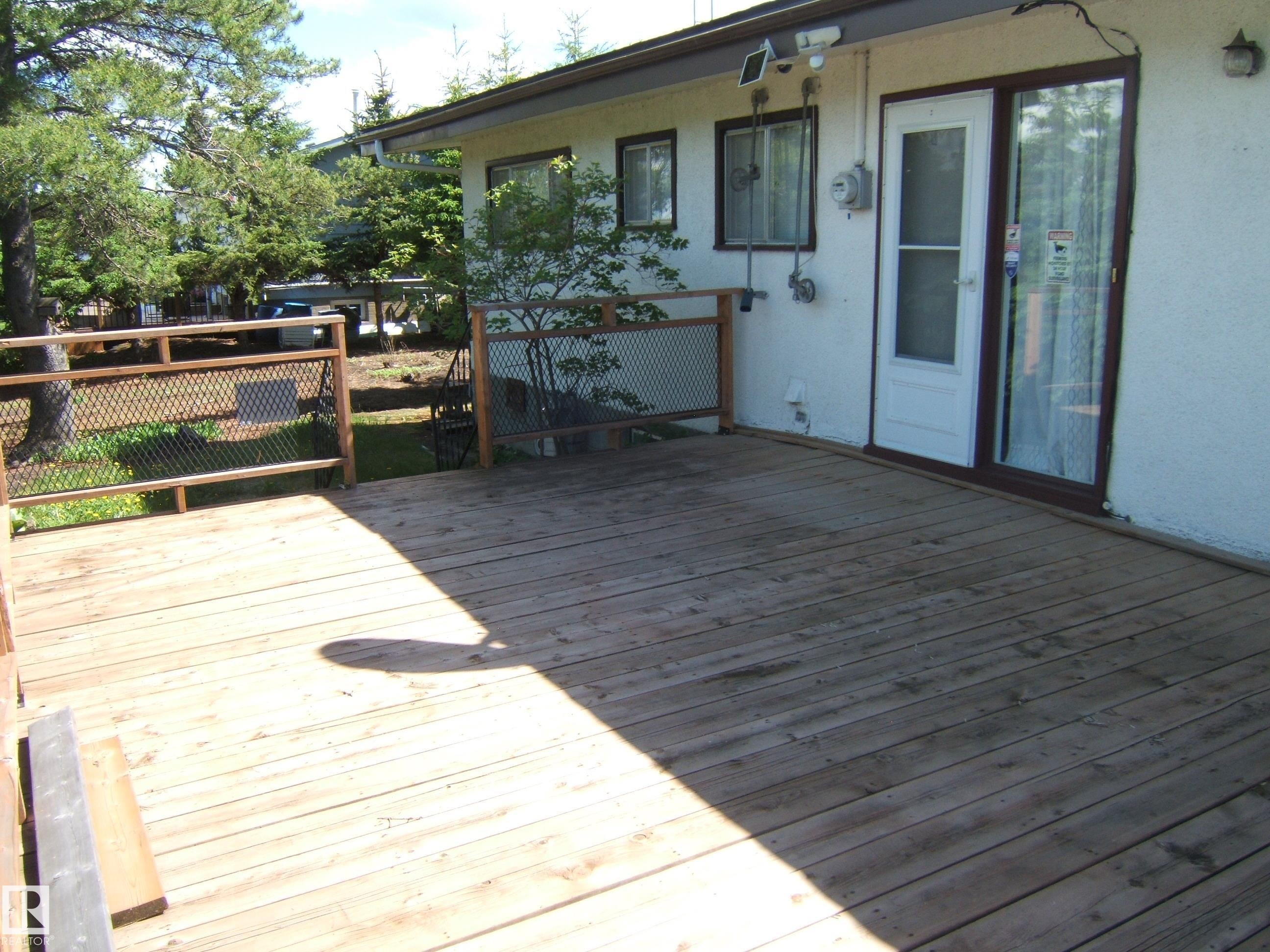 Expansive wood deck with a grid pattern railing, providing outdoor living space - 4910 53 Avenue, Willingdon, AB