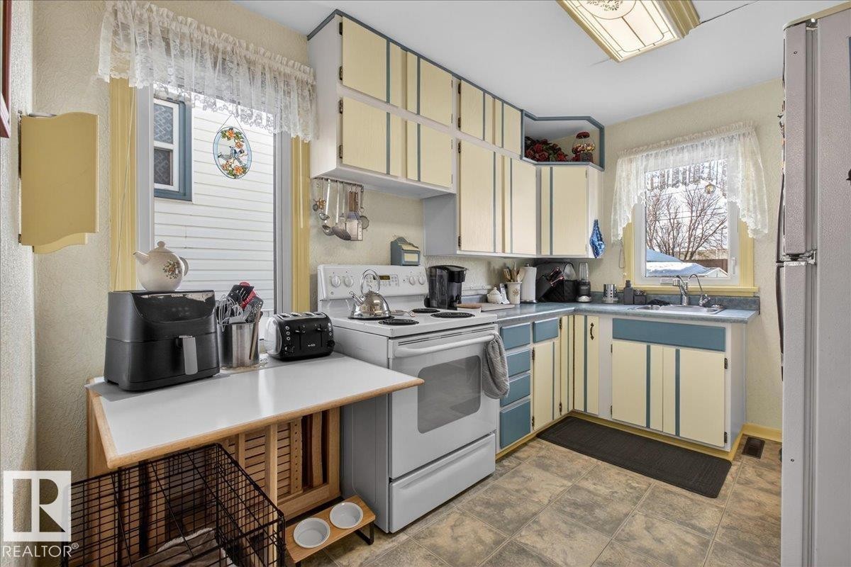 Kitchen featuring white range with electric cooktop, freestanding refrigerator, and light countertops - 11630 71 Street, Edmonton, AB - Indoor Photo Showing Kitchen