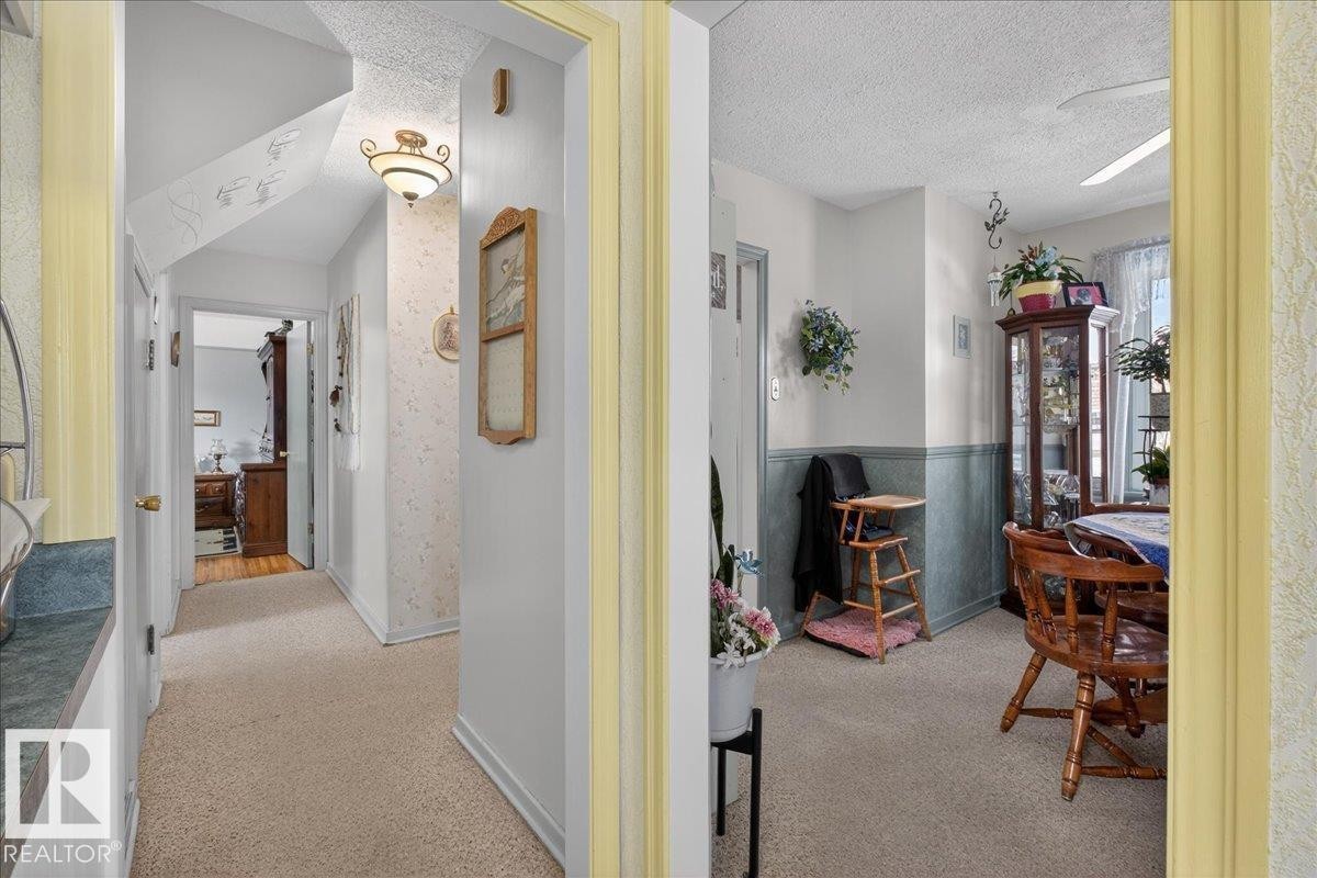 Hall featuring light carpet and a textured ceiling - 11630 71 Street, Edmonton, AB - Indoor
