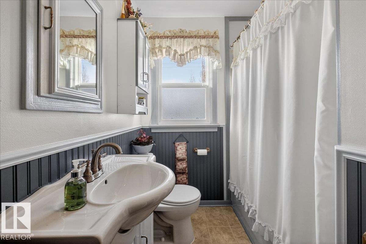 Bathroom featuring a wainscoted wall, a shower with shower curtain, vanity, and a textured wall - 11630 71 Street, Edmonton, AB - Indoor Photo Showing Bathroom