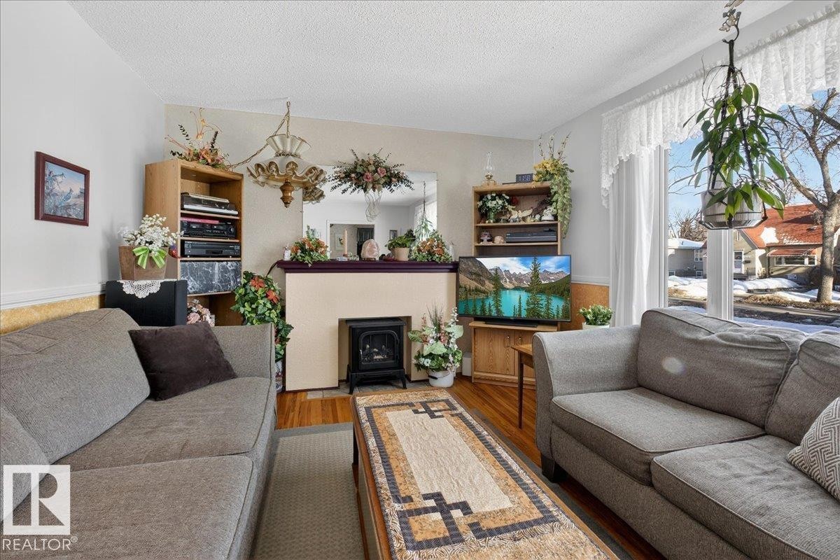 Living area featuring wood finished floors and a textured ceiling - 11630 71 Street, Edmonton, AB - Indoor Photo Showing Living Room With Fireplace