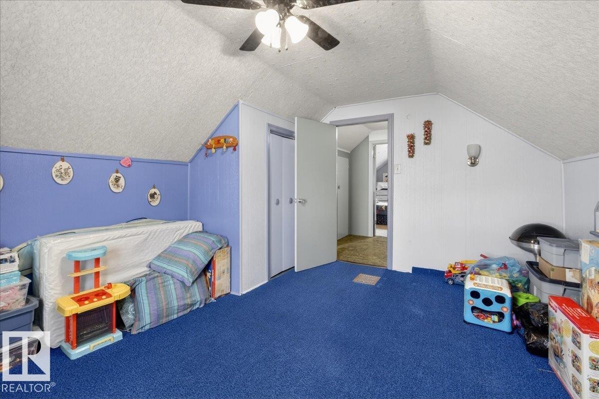Playroom featuring a textured ceiling, vaulted ceiling, carpet, and a ceiling fan - 11630 71 Street, Edmonton, AB - Indoor