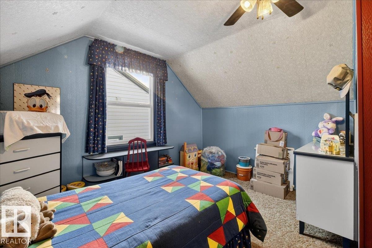Carpeted bedroom featuring lofted ceiling, a textured ceiling, and a ceiling fan - 11630 71 Street, Edmonton, AB - Indoor Photo Showing Bedroom