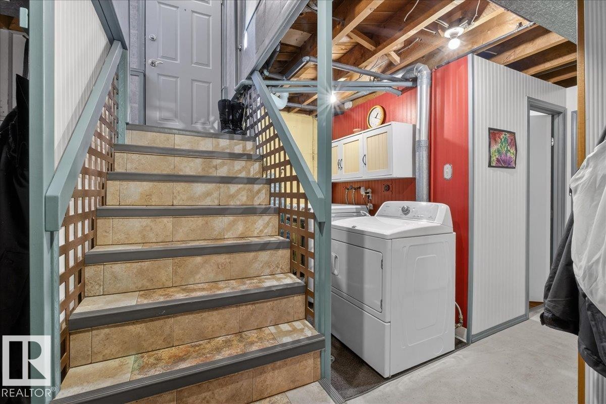 Washroom with unfinished concrete flooring, cabinet space, and washing machine and clothes dryer - 11630 71 Street, Edmonton, AB - Indoor Photo Showing Laundry Room