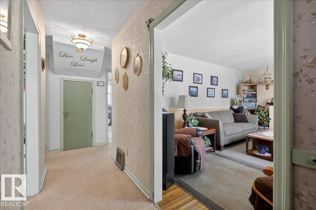 Hallway featuring a textured ceiling, carpet floors, and wallpapered walls - 11630 71 Street, Edmonton, AB - Indoor Photo Showing Other Room