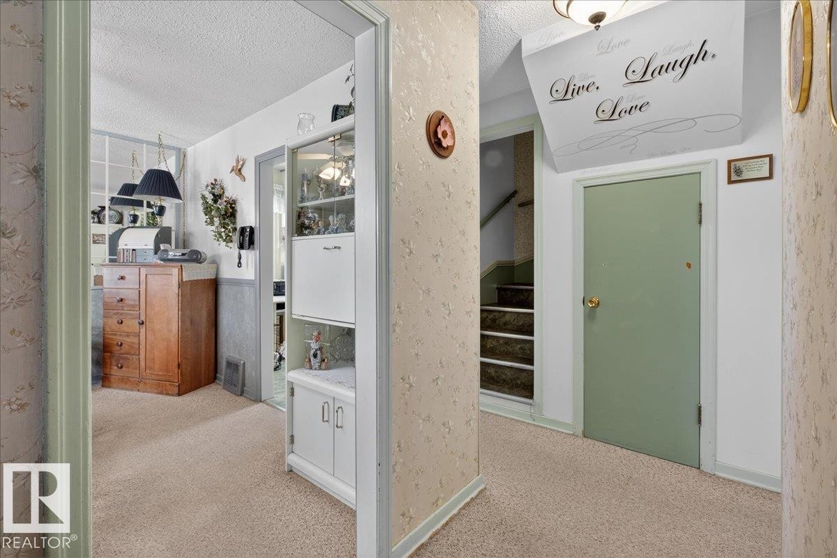 Hallway featuring light carpet, a textured ceiling, and stairs - 11630 71 Street, Edmonton, AB - Indoor Photo Showing Other Room