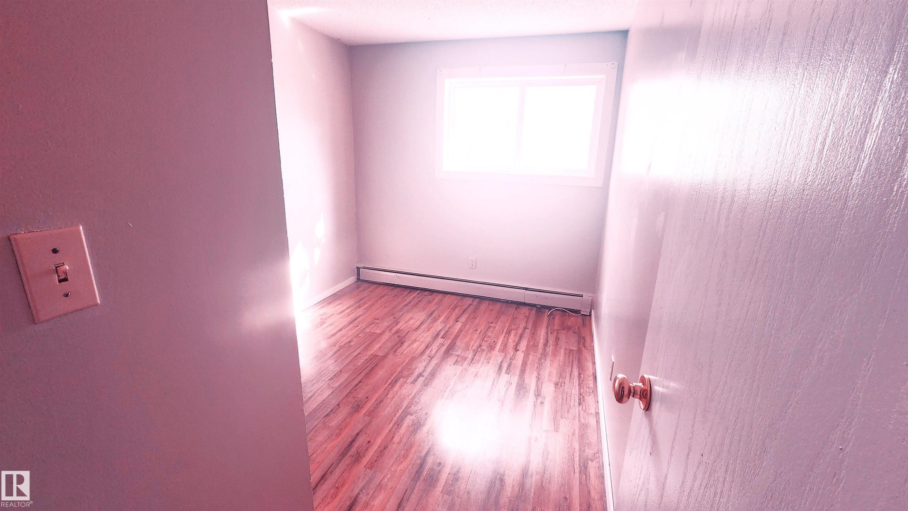 Empty room with baseboard heating and wood finished floors - 2 11265 31 Avenue, Edmonton, AB - Indoor Photo Showing Other Room
