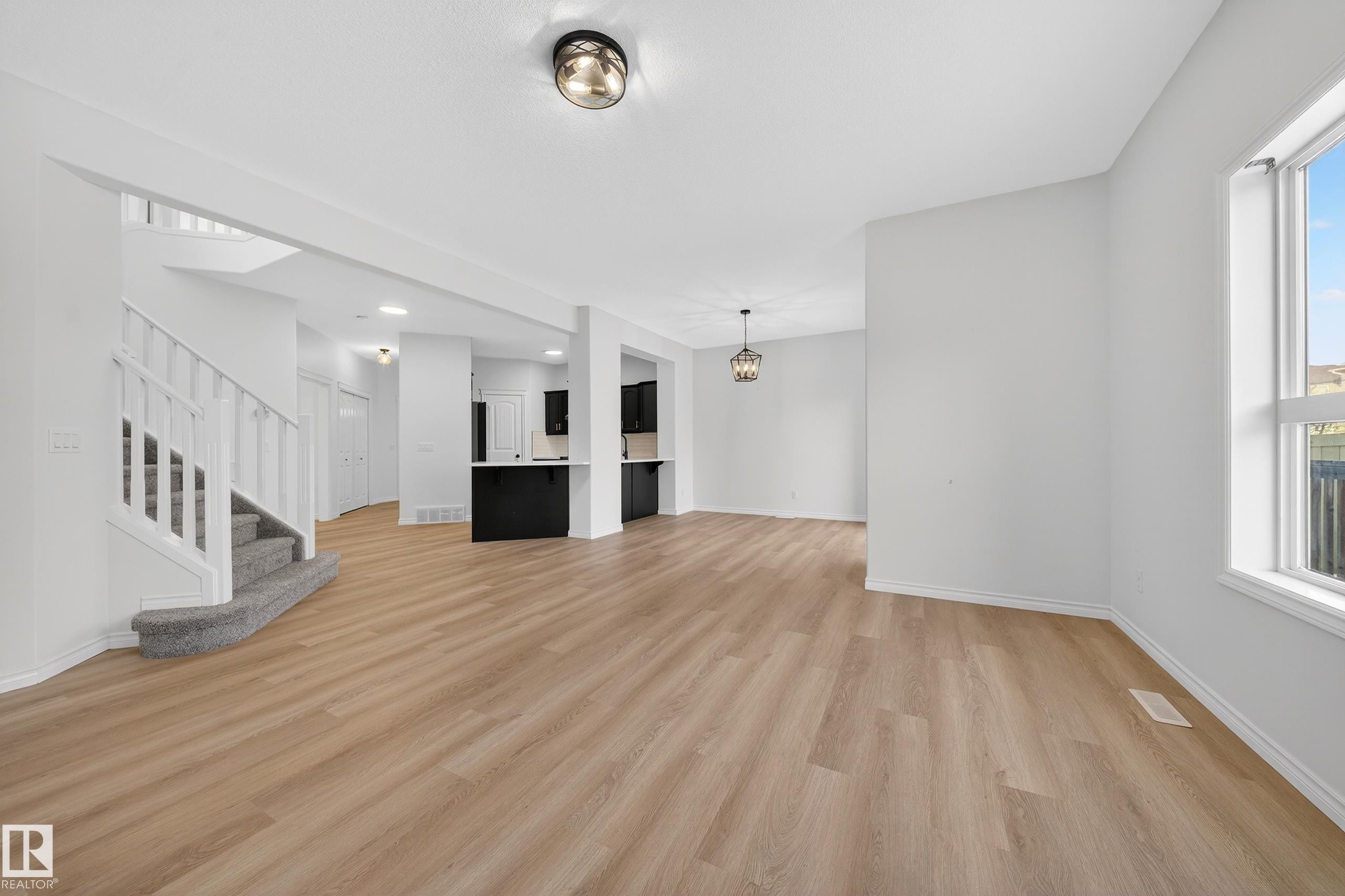 Unfurnished living room featuring stairs, light wood finished floors, and a chandelier - 1741 63A Street, Edmonton, AB