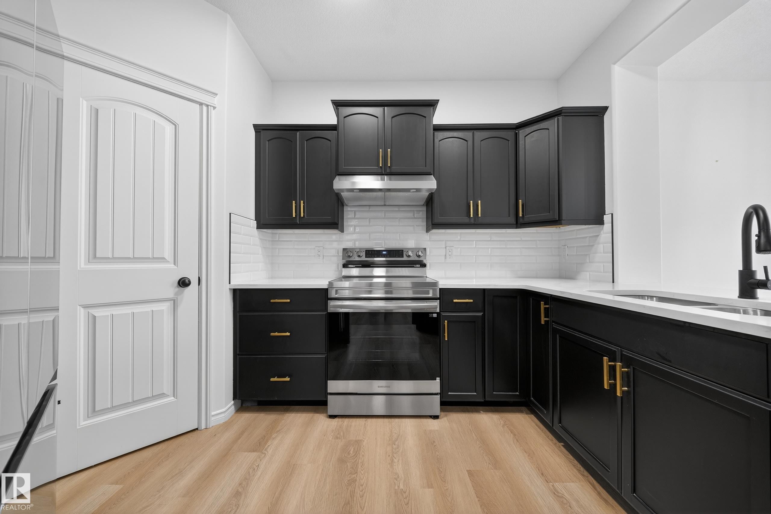 Kitchen featuring dark cabinets, electric range, light stone counters, and light wood-style floors - 1741 63A Street, Edmonton, AB - Indoor Photo Showing Kitchen