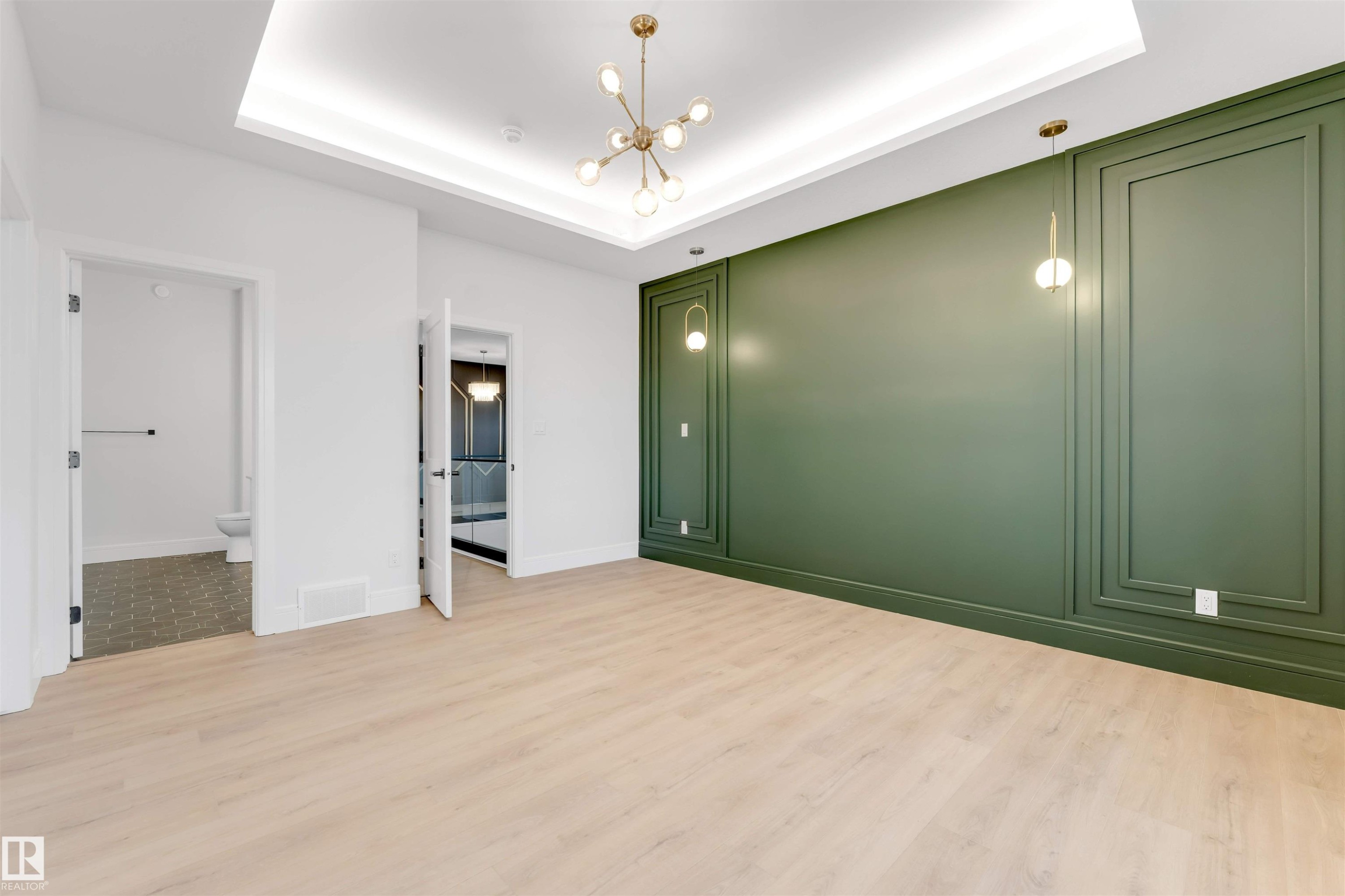 Unfurnished bedroom featuring wood finished floors, a chandelier, ensuite bathroom, and a tray ceiling - 150 Creekside Lane, Leduc, AB - Indoor Photo Showing Other Room