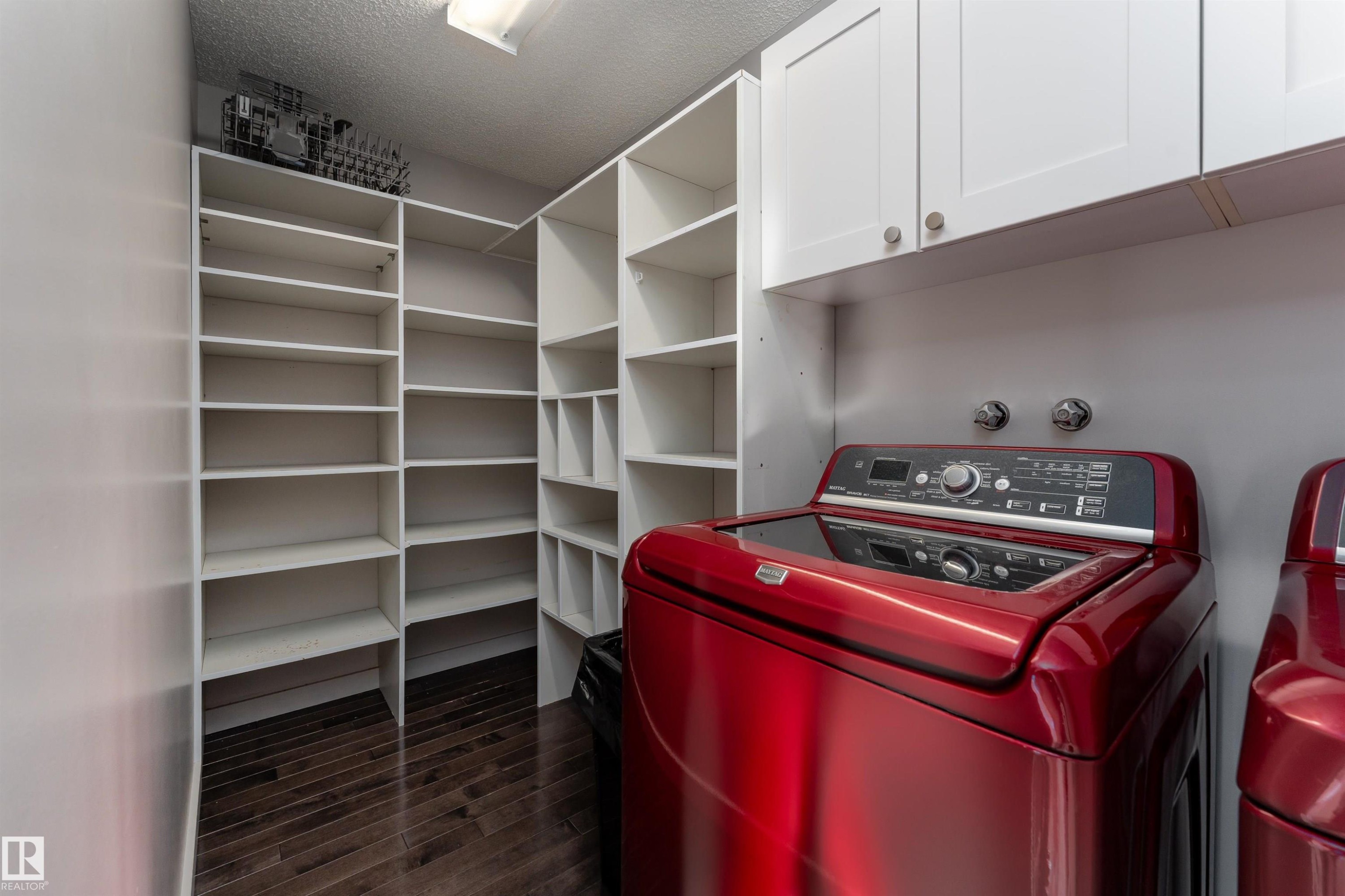 Washroom featuring washer / clothes dryer, dark wood-type flooring, a textured ceiling, and cabinet space - 174 Oeming Road, Edmonton, AB - Indoor With Storage