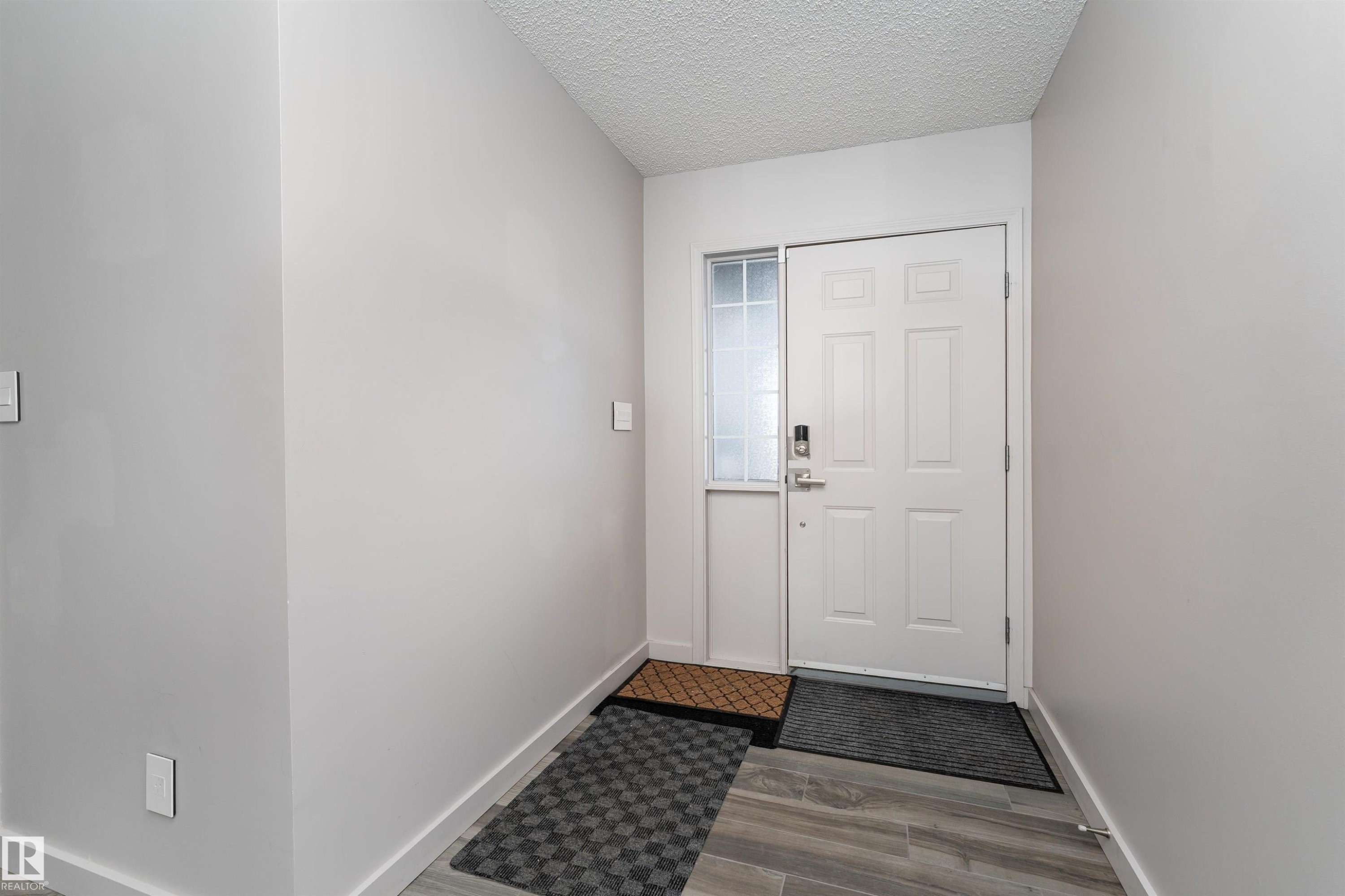 Doorway with a textured ceiling and wood finished floors - 174 Oeming Road, Edmonton, AB - Indoor Photo Showing Other Room