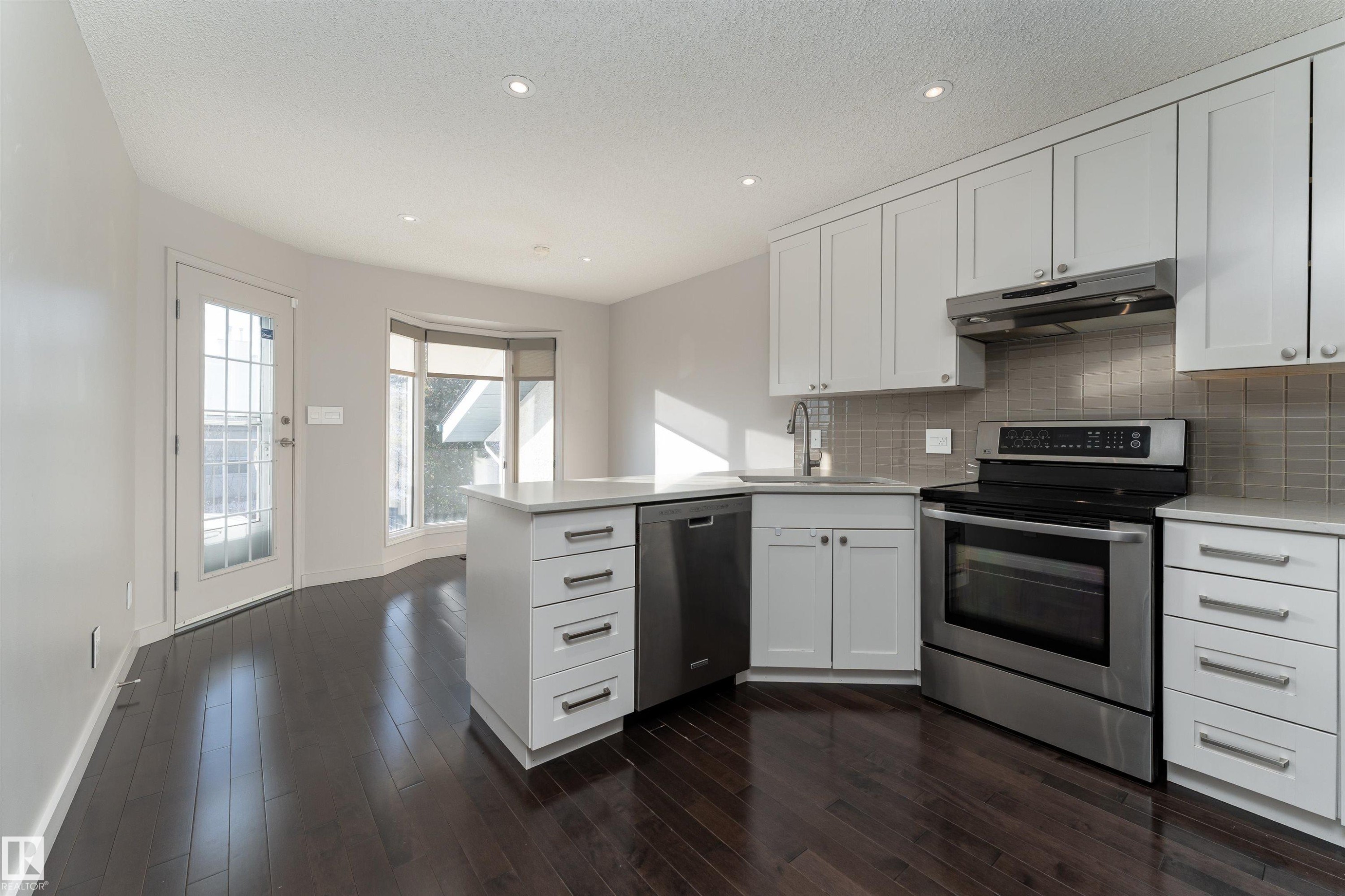 Kitchen with a peninsula, white cabinets, appliances with stainless steel finishes, recessed lighting, and a textured ceiling - 174 Oeming Road, Edmonton, AB - Indoor Photo Showing Kitchen