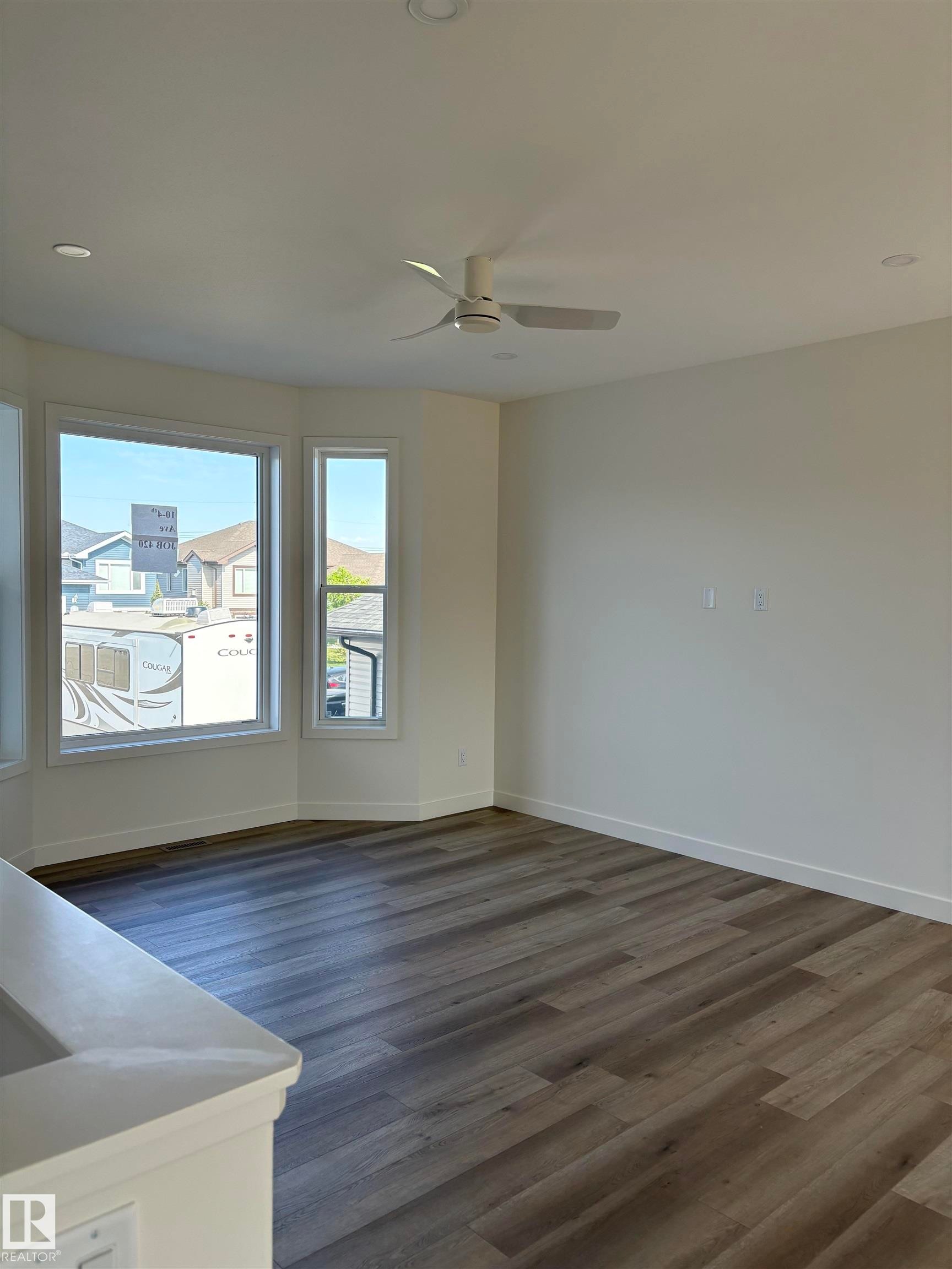Spacious living area featuring wood-finish flooring, a contemporary ceiling fan, and recessed lighting - 6 4 Avenue, Hay Lakes, AB