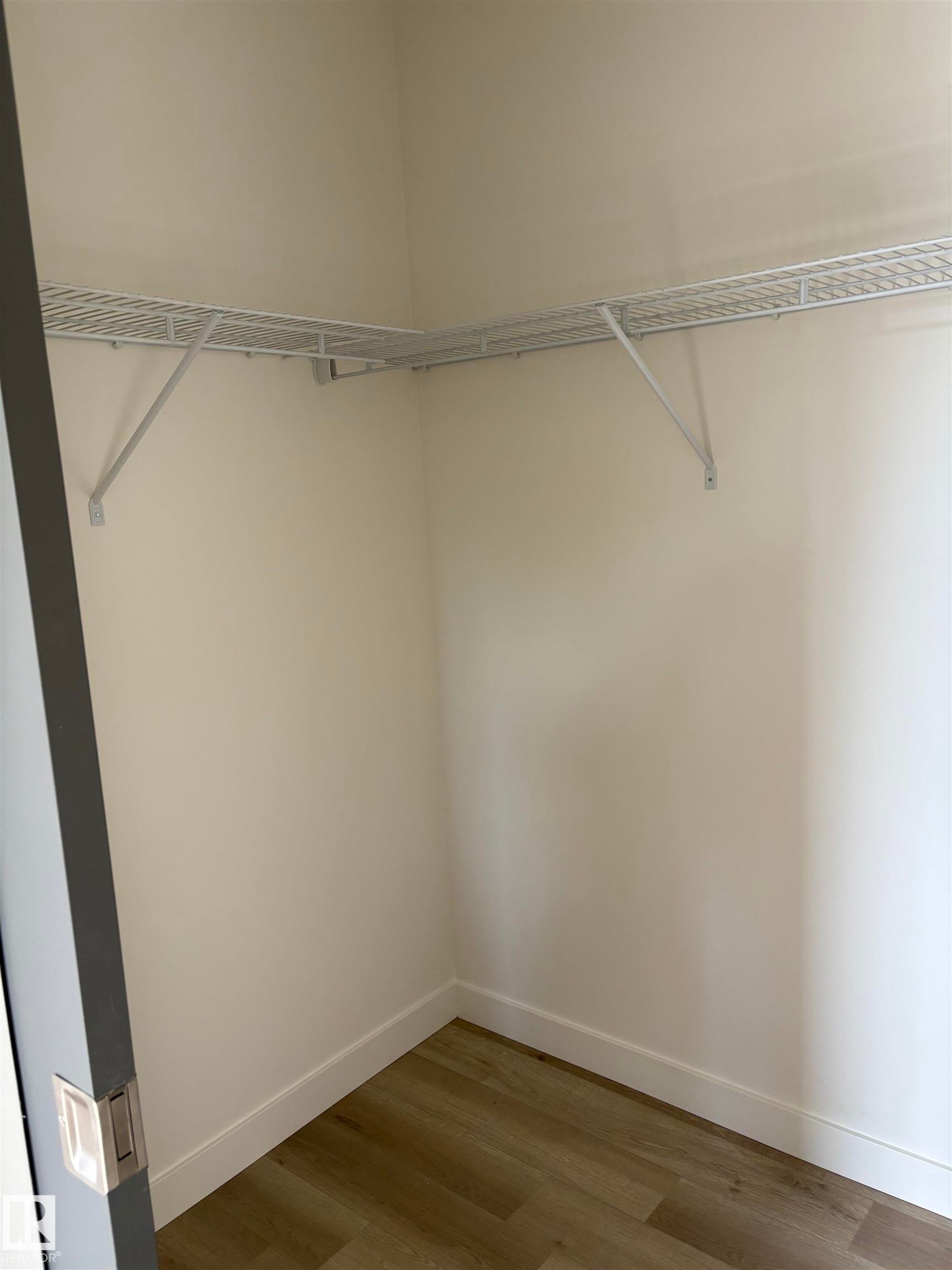 Built-in wire shelving system with white finish, smooth white walls, white baseboards, and wood-finish flooring - 6 4 Avenue, Hay Lakes, AB