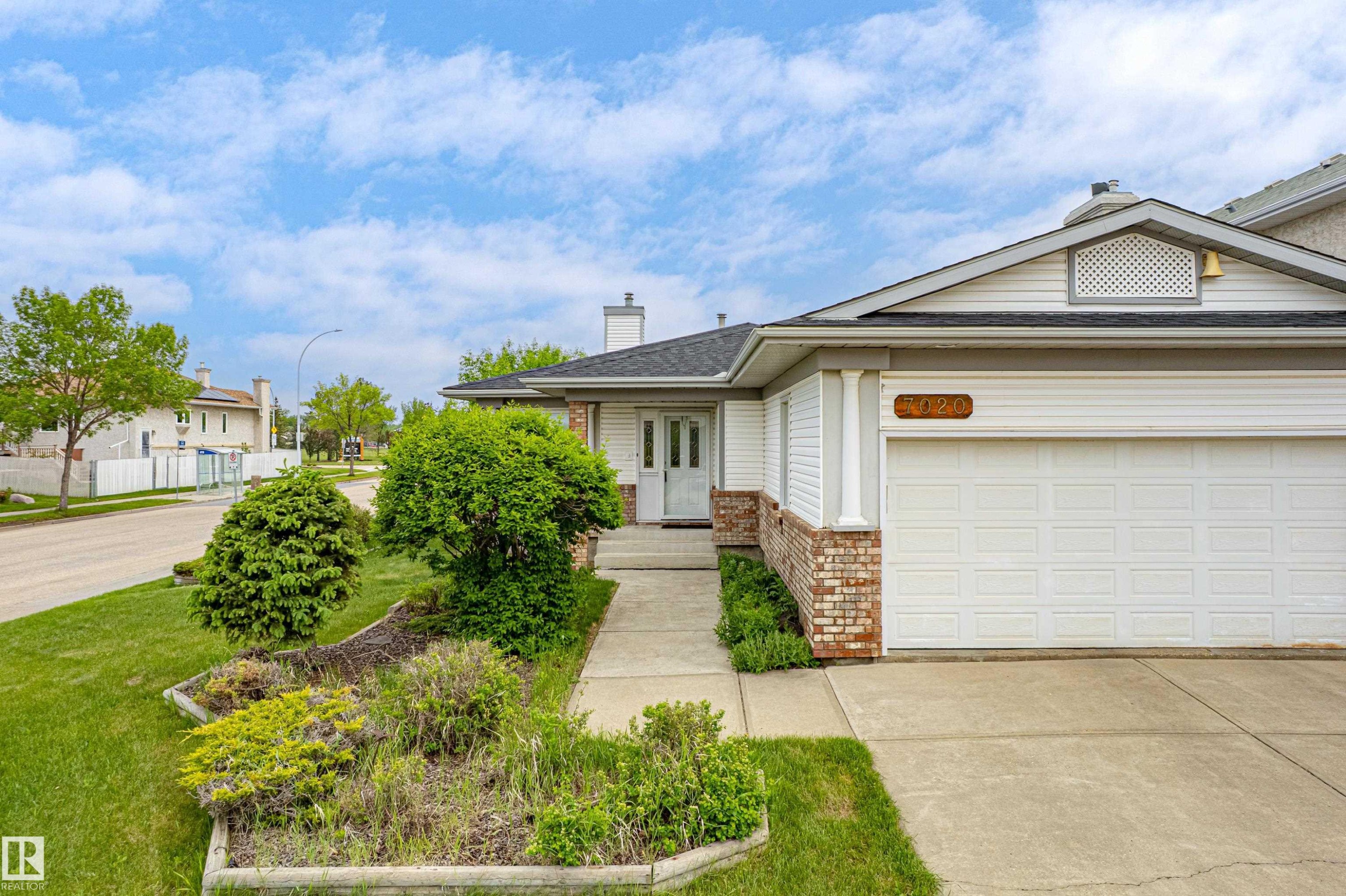 Front exterior with attached garage, white siding, and brick accents - 7020 157 Avenue, Edmonton, AB - Outdoor