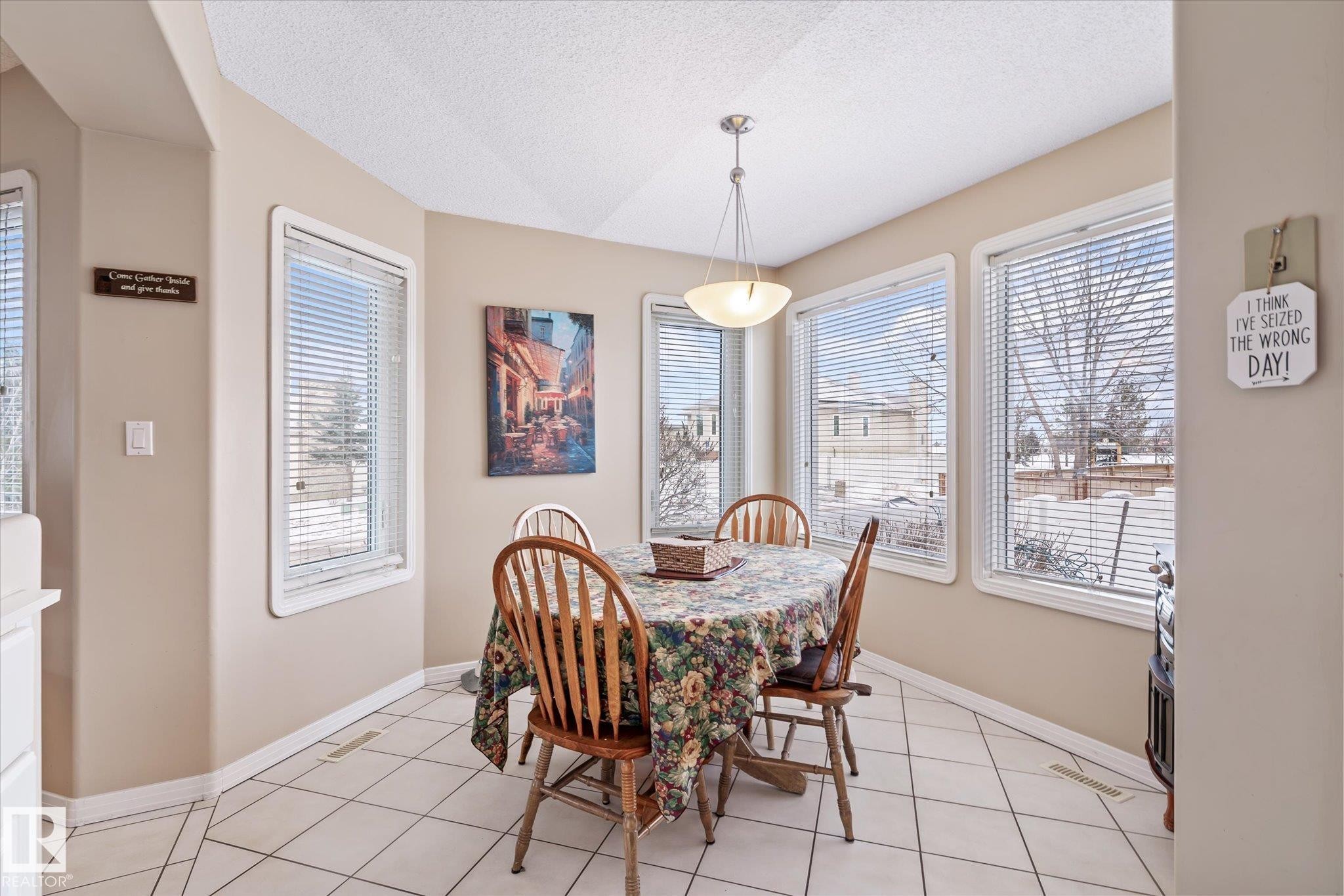Dining room with a textured ceiling, light tile patterned floors, and plenty of natural light - 7020 157 Avenue, Edmonton, AB - Indoor Photo Showing Dining Room