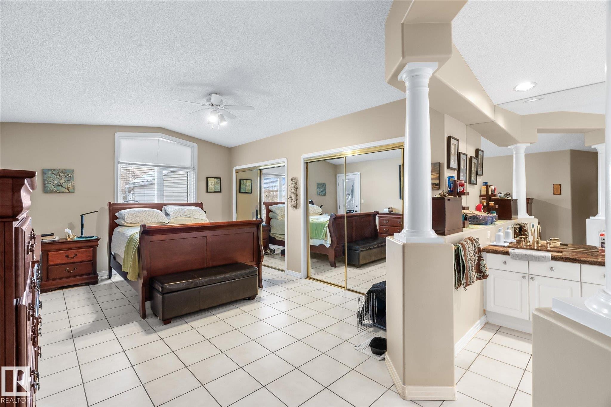Bedroom featuring two closets, light tile patterned flooring, a textured ceiling, ceiling fan, and vaulted ceiling - 7020 157 Avenue, Edmonton, AB - Indoor Photo Showing Bedroom