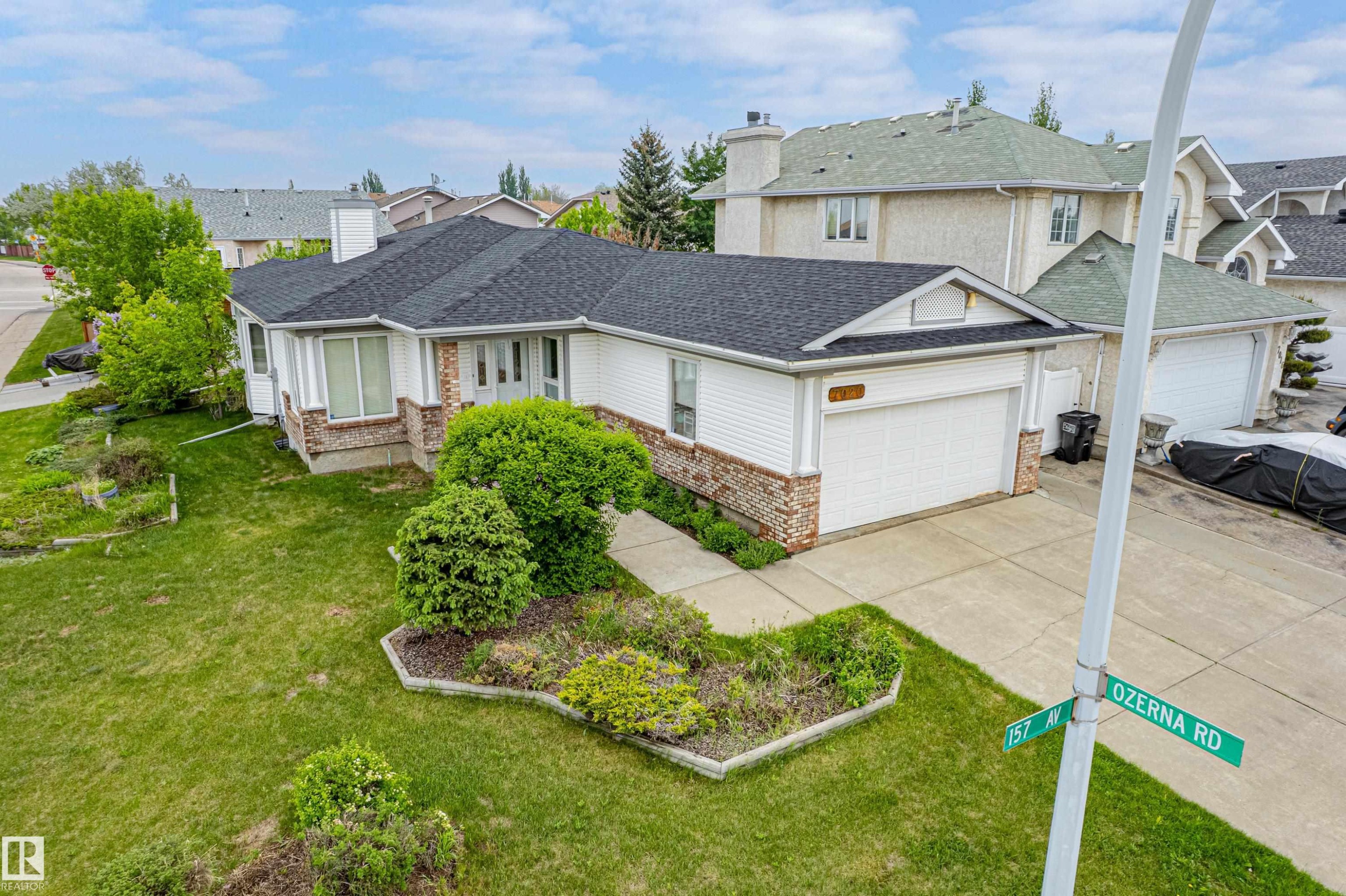 Single-story residence featuring a dark shingle roof, white siding, and brick accents - 7020 157 Avenue, Edmonton, AB - Outdoor
