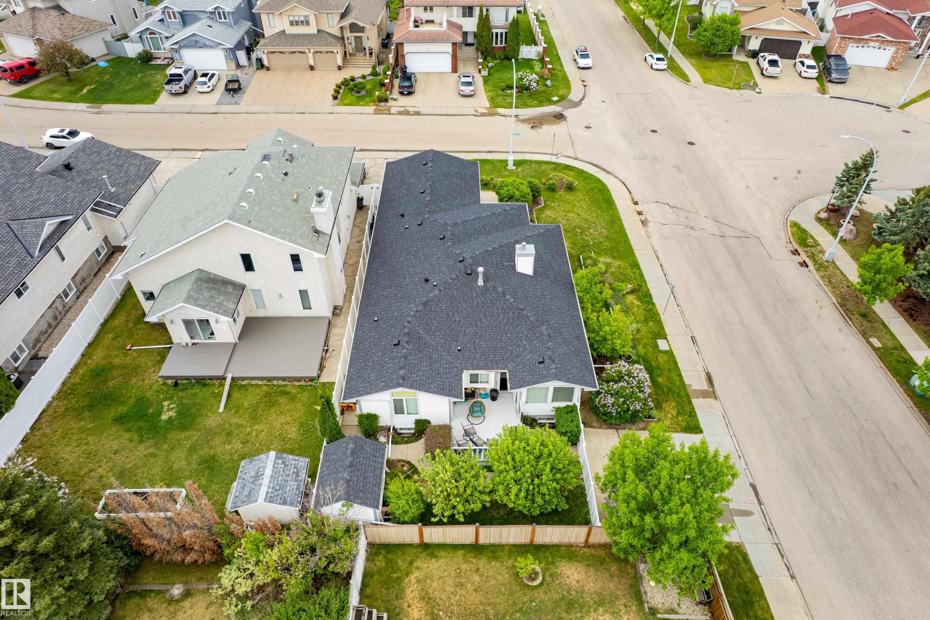 Property featuring a dark shingle roof, white exterior siding, and a rear deck with a sunroom addition - 7020 157 Avenue, Edmonton, AB - Outdoor With View