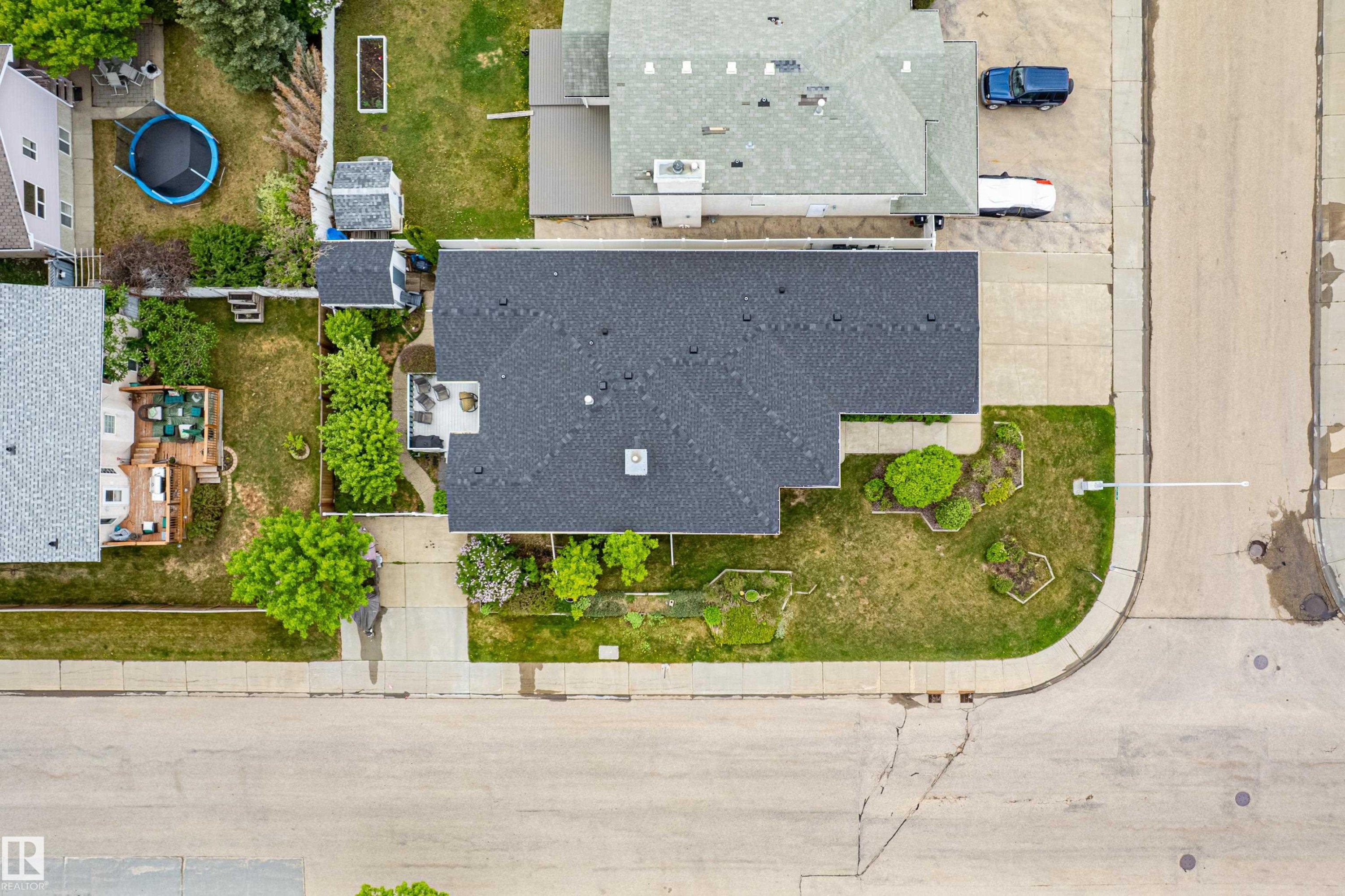 Property featuring a dark shingle roof, concrete driveway, and front lawn with landscaped planting beds - 7020 157 Avenue, Edmonton, AB - Outdoor