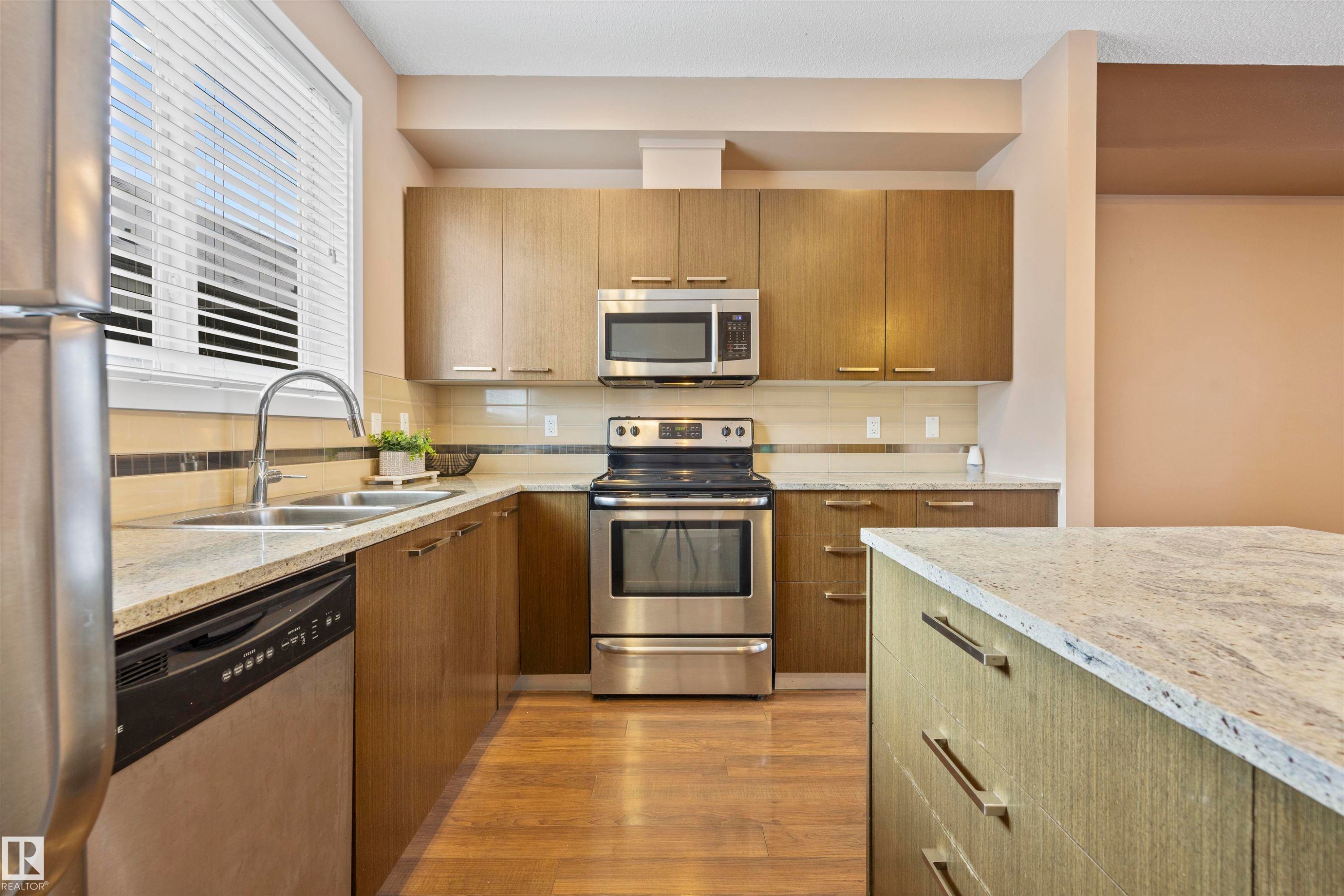 Kitchen featuring stainless steel appliances, light stone counters, dark wood-type flooring, backsplash, and modern cabinets - 56 655 Watt Boulevard, Edmonton, AB - Indoor Photo Showing Kitchen With Stainless Steel Kitchen With Double Sink