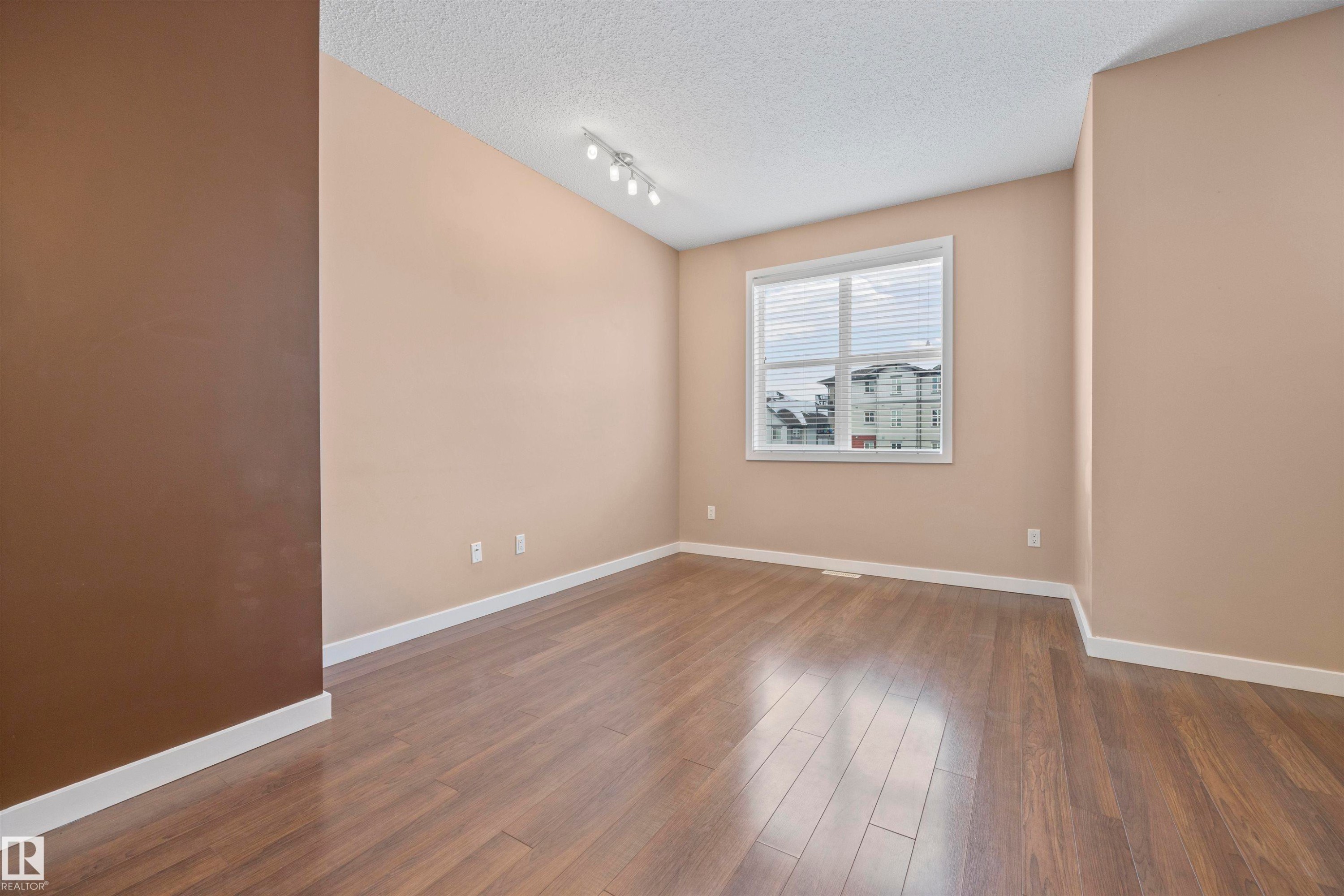 Empty room featuring a textured ceiling and dark wood-type flooring - 56 655 Watt Boulevard, Edmonton, AB - Indoor Photo Showing Other Room