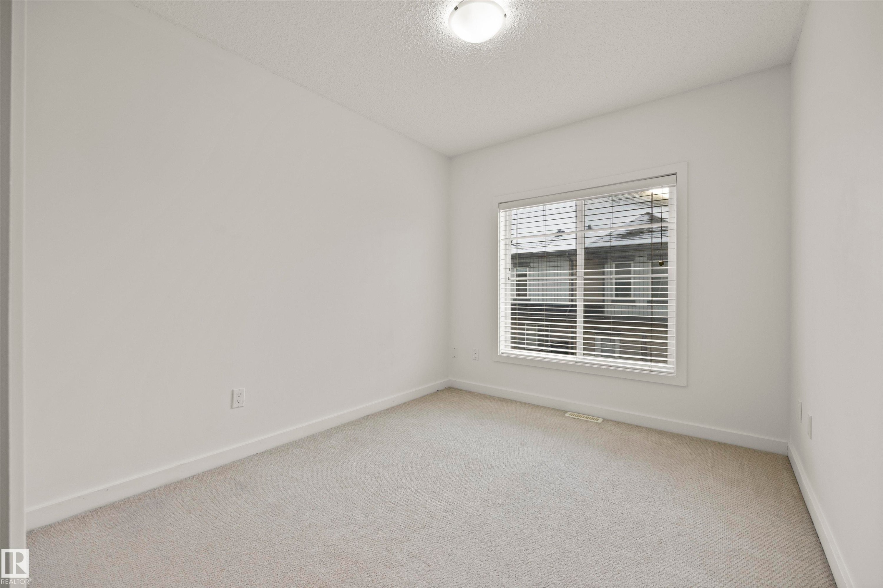 Empty room featuring a textured ceiling and light carpet - 56 655 Watt Boulevard, Edmonton, AB - Indoor Photo Showing Other Room