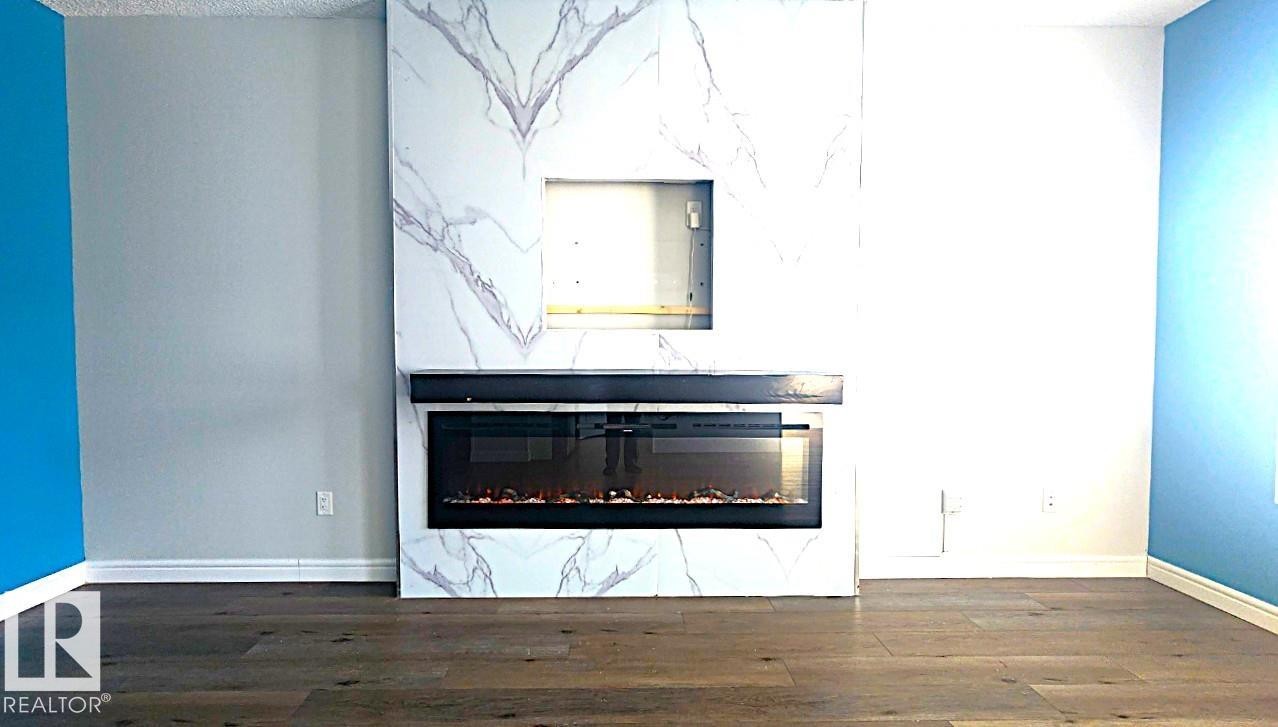 Detailed view of wood finished floors and a glass covered fireplace - 4610 Kinsella Landing Sw, Edmonton, AB - Indoor With Fireplace