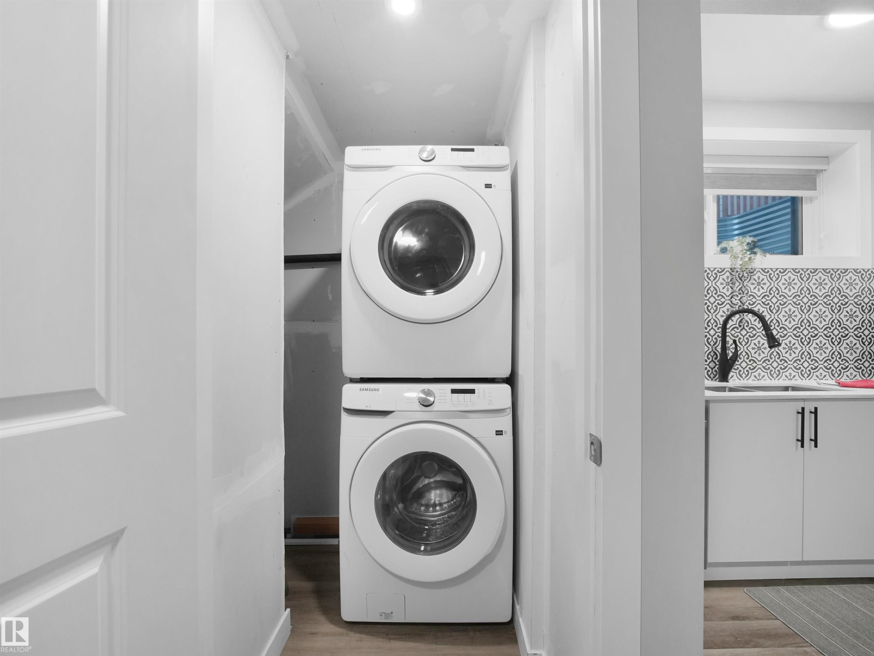 Legal basement suite laundry featuring estacked washer and dryer, light wood-type flooring, and recessed lighting - 10913 159 Street, Edmonton, AB - Indoor Photo Showing Laundry Room