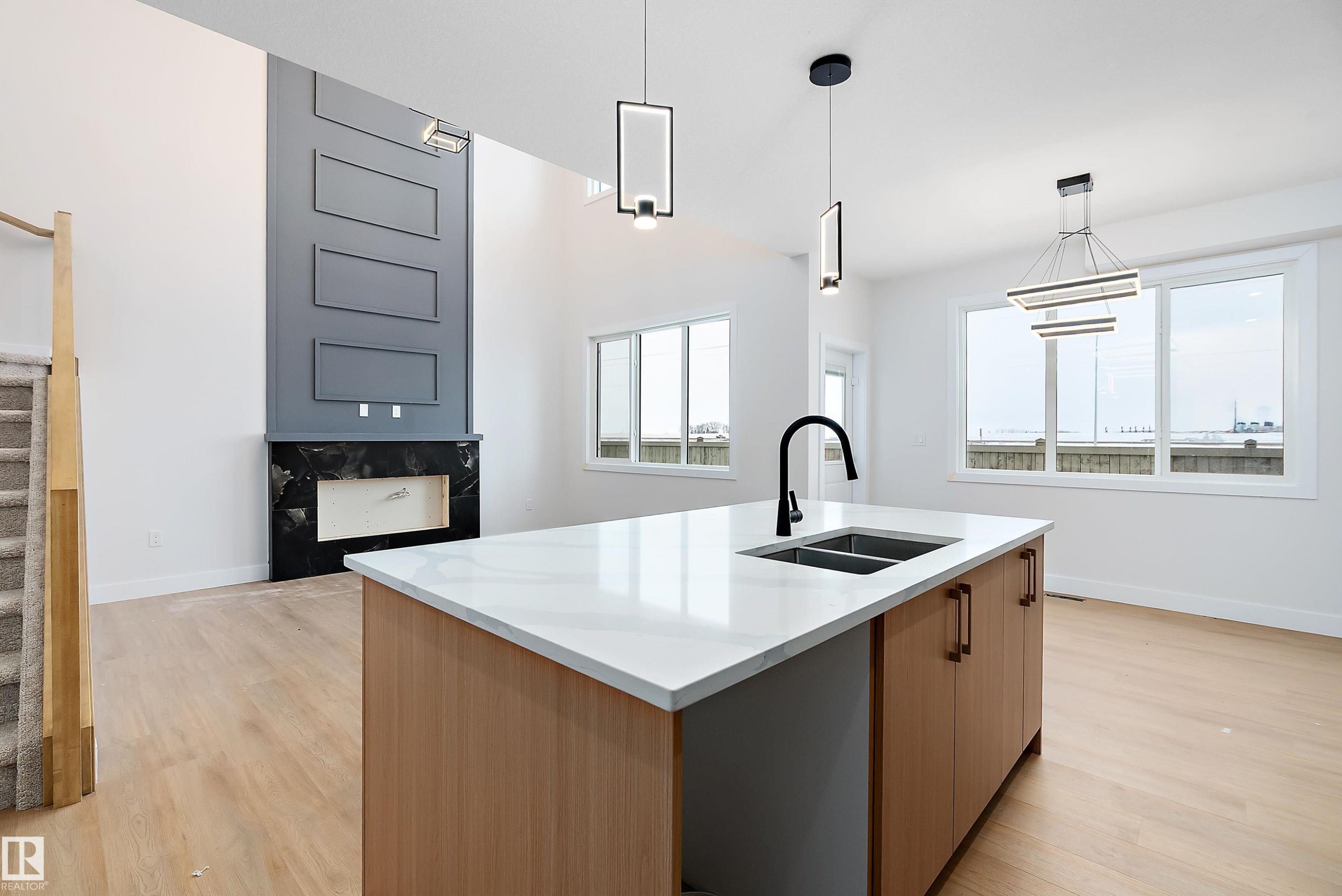 Kitchen with pendant lighting, light wood finished floors, light stone counters, a kitchen island with sink, and open floor plan - 38 Astoria Place, Devon, AB - Indoor Photo Showing Kitchen With Double Sink