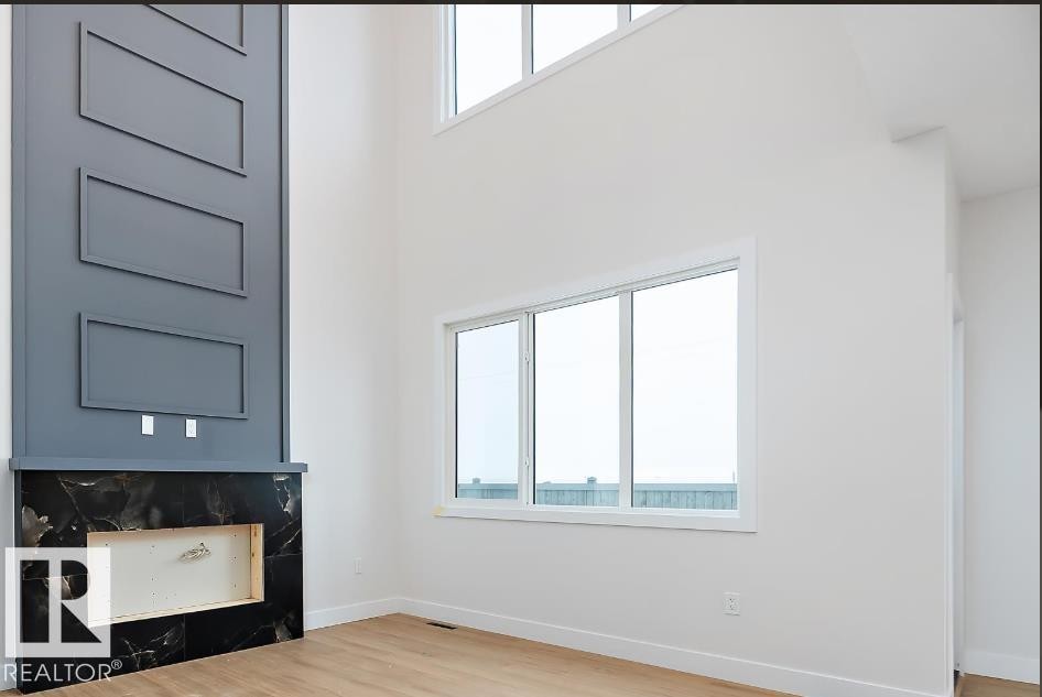 Unfurnished living room with a towering ceiling and light wood-style flooring - 38 Astoria Place, Devon, AB - Indoor Photo Showing Other Room