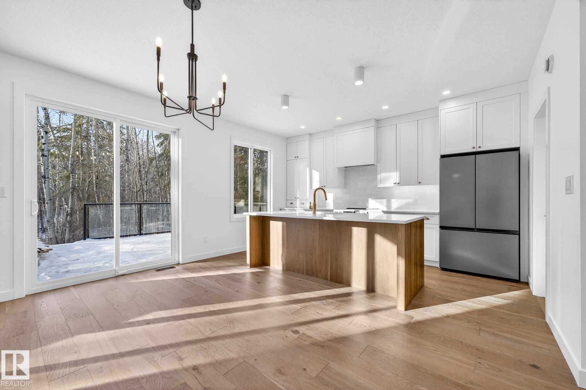 Kitchen featuring white cabinets, freestanding refrigerator, a kitchen island with sink, light wood-style flooring, and recessed lighting - 132 Heron Point Close, Rural Wetaskiwin County, AB - Indoor Photo Showing Kitchen