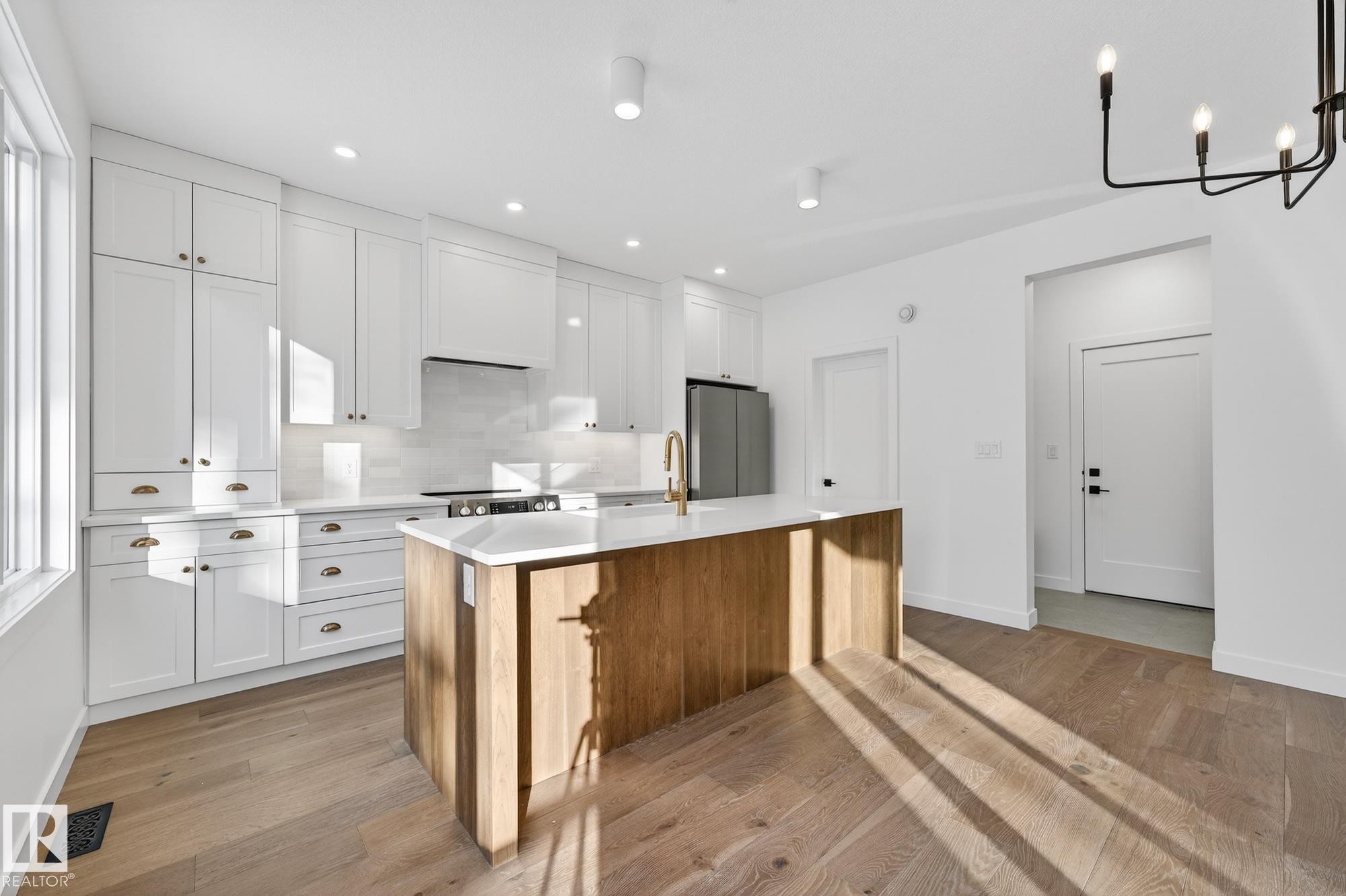 Kitchen featuring white cabinetry, a center island with sink, appliances with stainless steel finishes, backsplash, and brown cabinetry - 132 Heron Point Close, Rural Wetaskiwin County, AB - Indoor Photo Showing Kitchen With Upgraded Kitchen