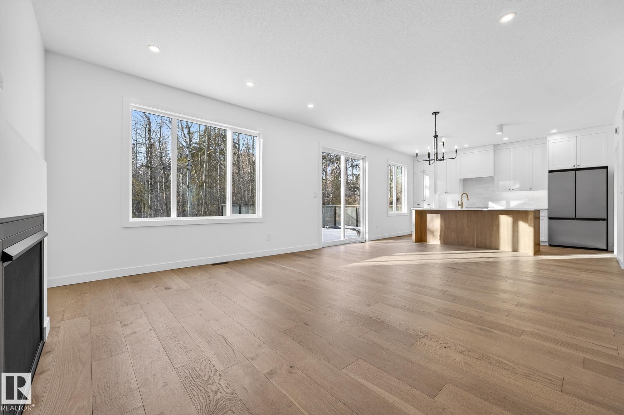 Unfurnished living room featuring a chandelier, recessed lighting, light wood finished floors, and a fireplace - 132 Heron Point Close, Rural Wetaskiwin County, AB - Indoor