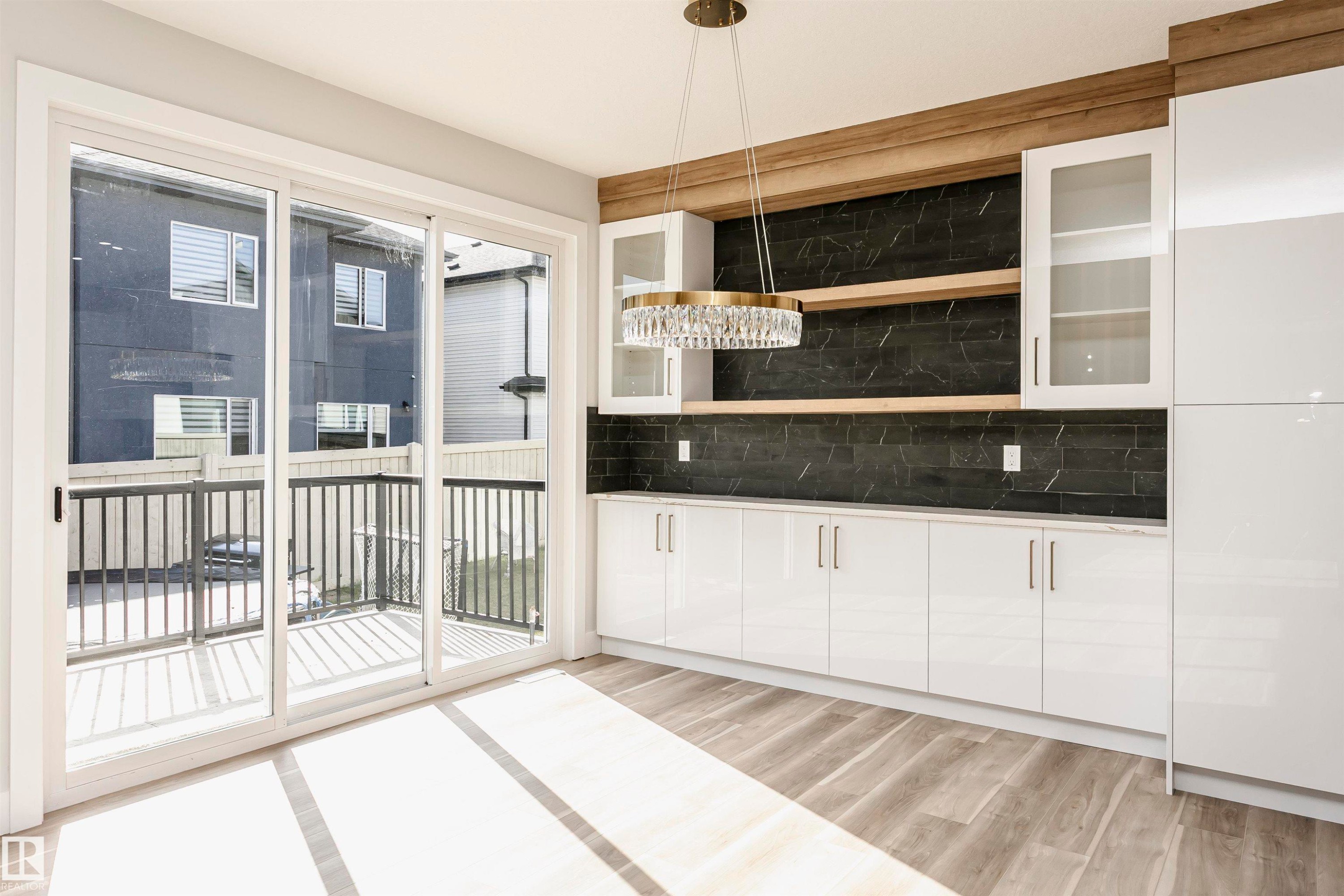 Bar with white cabinetry, pendant lighting, light wood-type flooring, glass insert cabinets, and decorative backsplash - 1723 19 Street, Edmonton, AB - Indoor