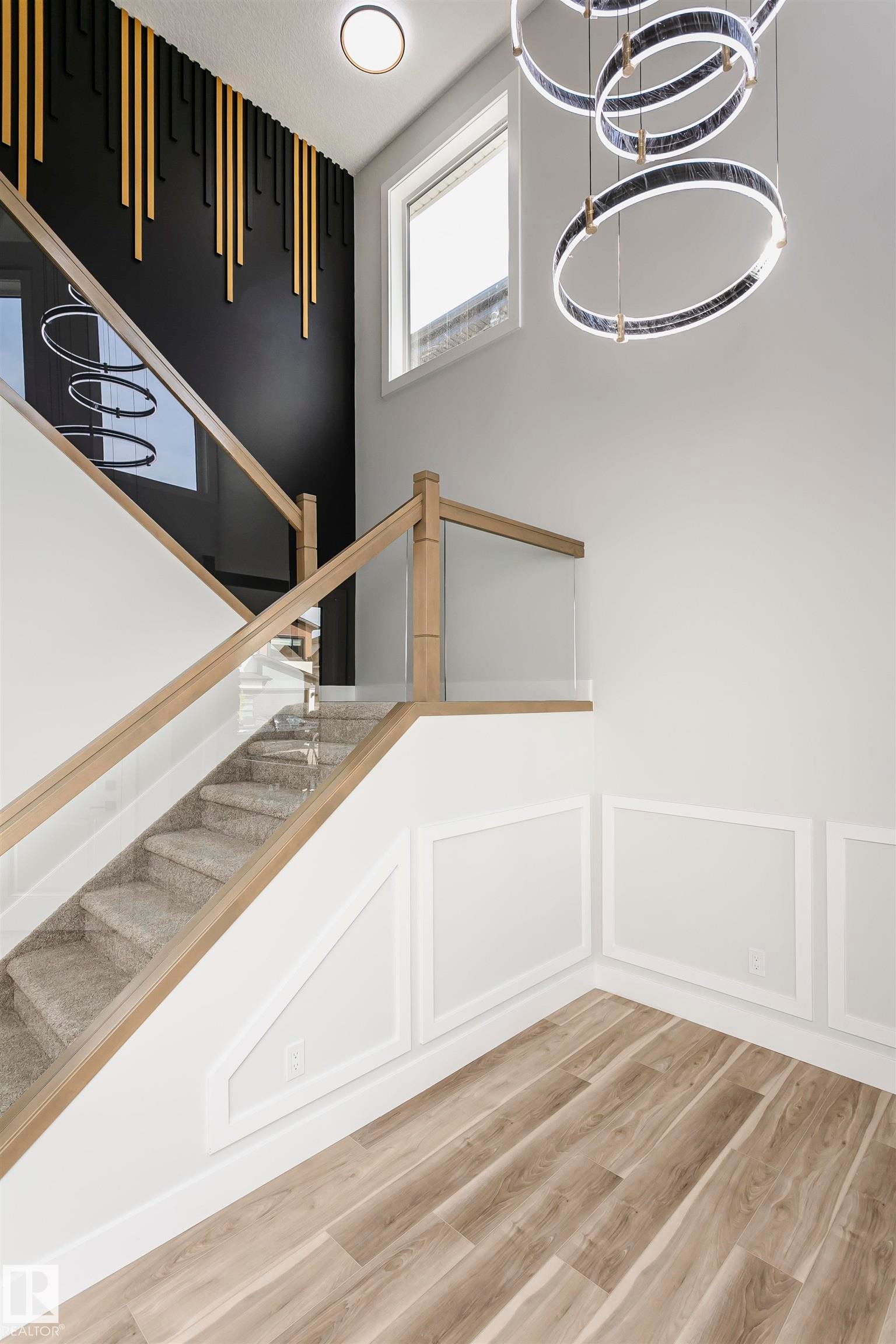 Staircase featuring LVP finished floors, a chandelier, and a decorative wall - 1723 19 Street, Edmonton, AB - Indoor Photo Showing Other Room