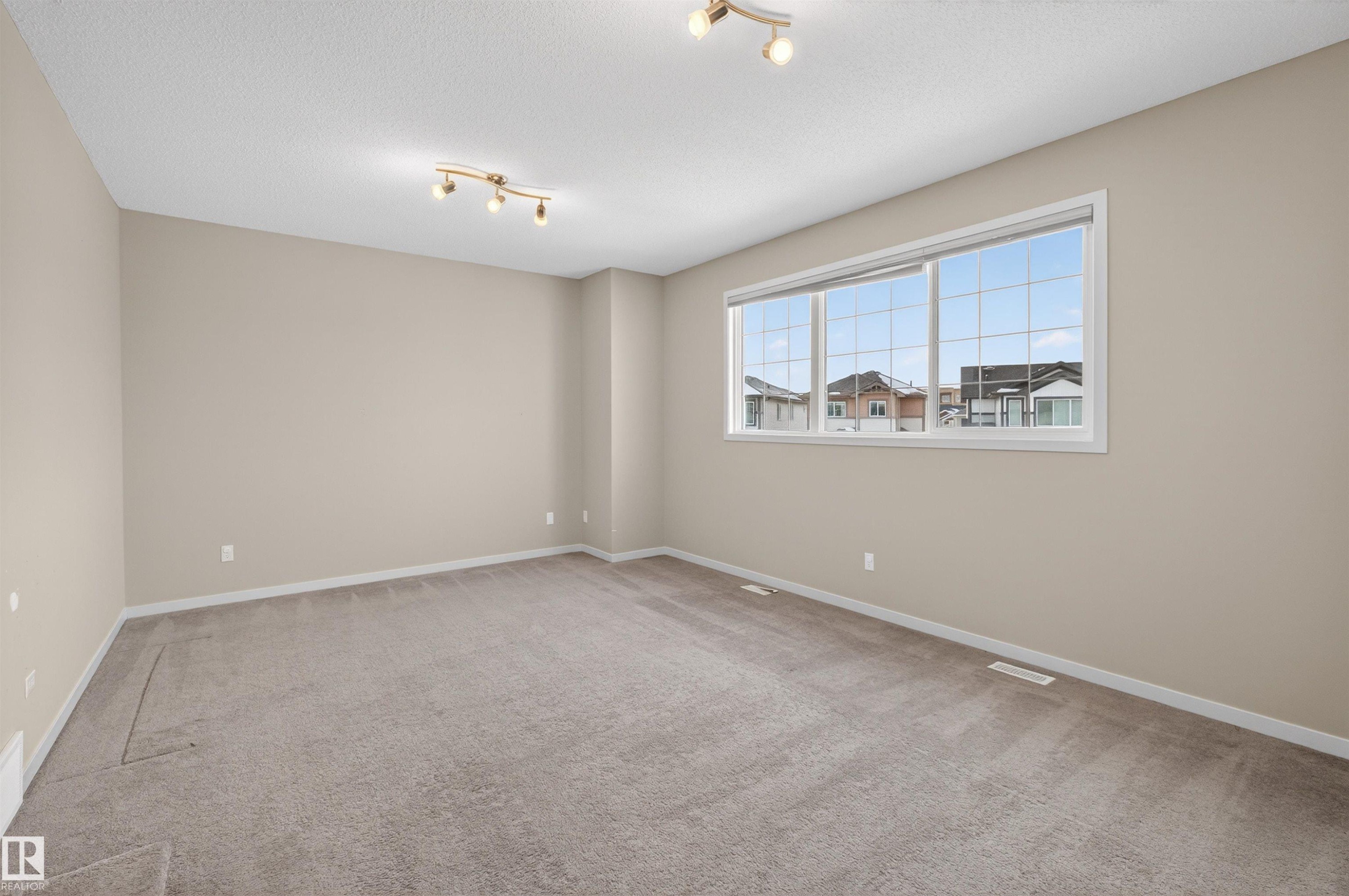 Unfurnished room with light carpet and rail lighting - 4723 Alwood Bend Bend Sw, Edmonton, AB - Indoor Photo Showing Other Room
