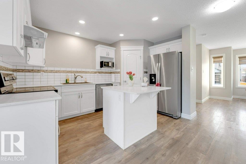 Kitchen with white cabinets, stainless steel appliances, a center island, and light wood-type flooring - 1423 24 Street, Edmonton, AB - Indoor Photo Showing Kitchen With Upgraded Kitchen