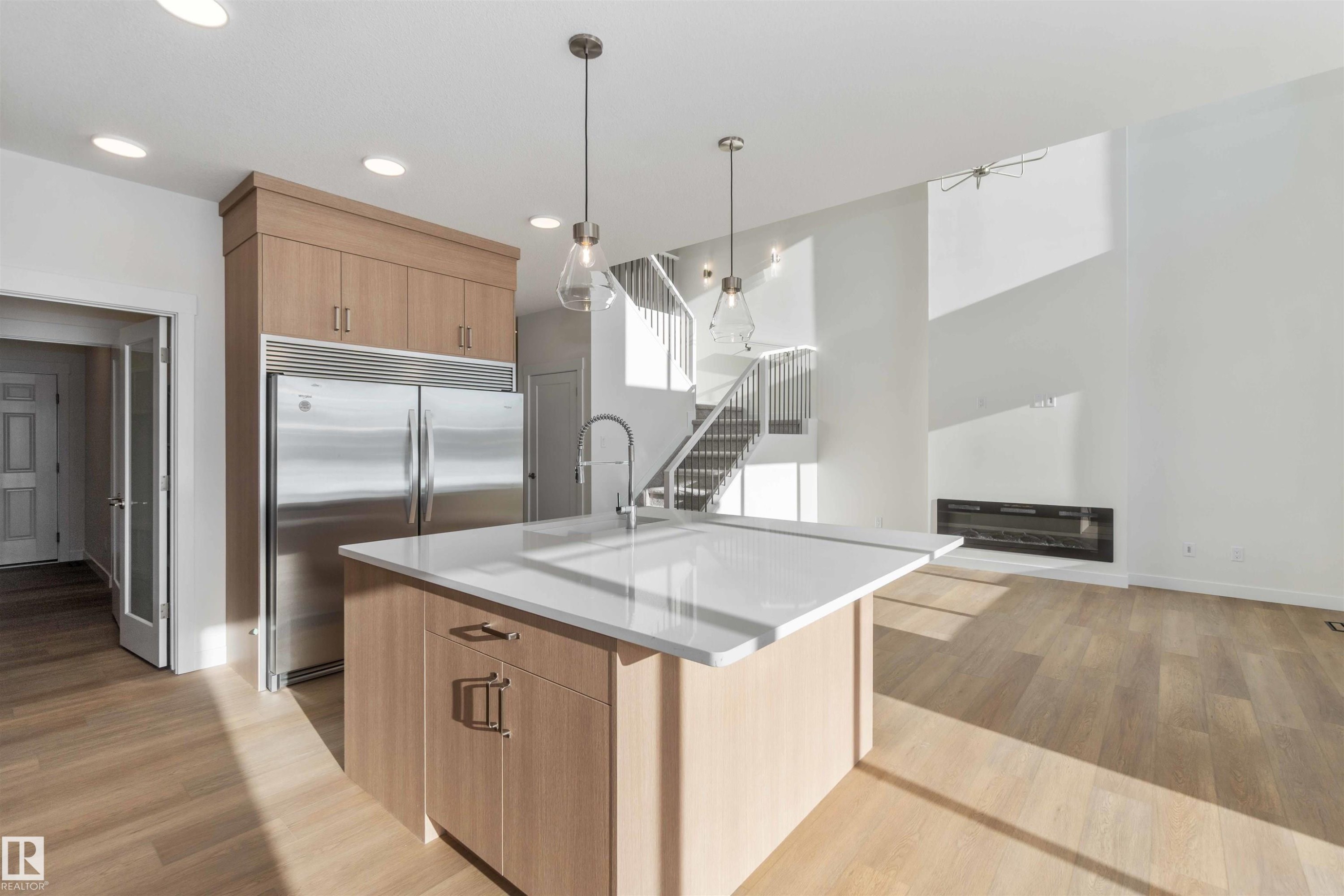 Kitchen featuring built in refrigerator, decorative light fixtures, light wood-type flooring, an island with sink, and modern cabinets - 2215 4 Avenue, Edmonton, AB - Indoor Photo Showing Kitchen With Upgraded Kitchen