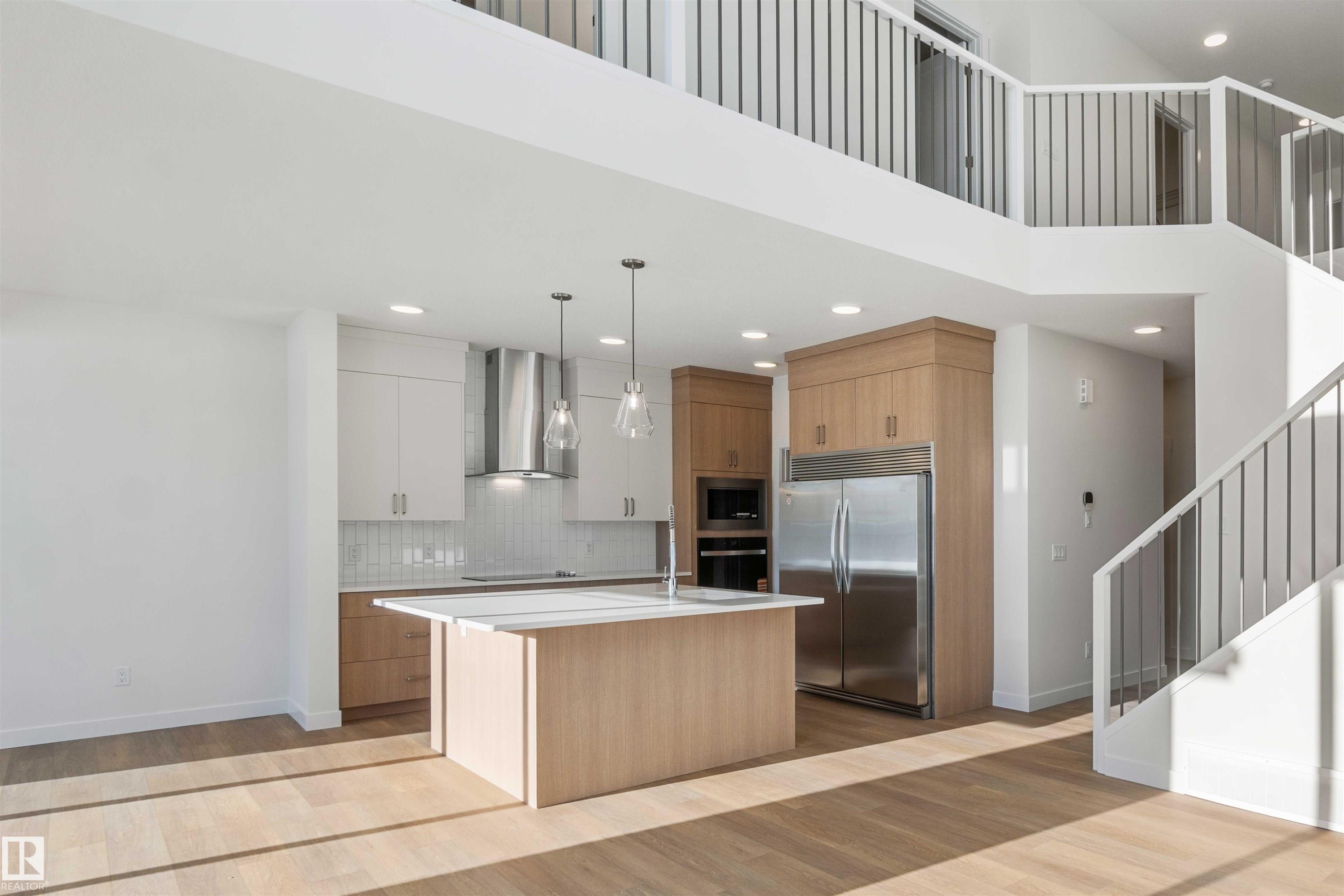 Kitchen with modern cabinets, an island with sink, black appliances, wall chimney exhaust hood, and recessed lighting - 2215 4 Avenue, Edmonton, AB - Indoor Photo Showing Kitchen