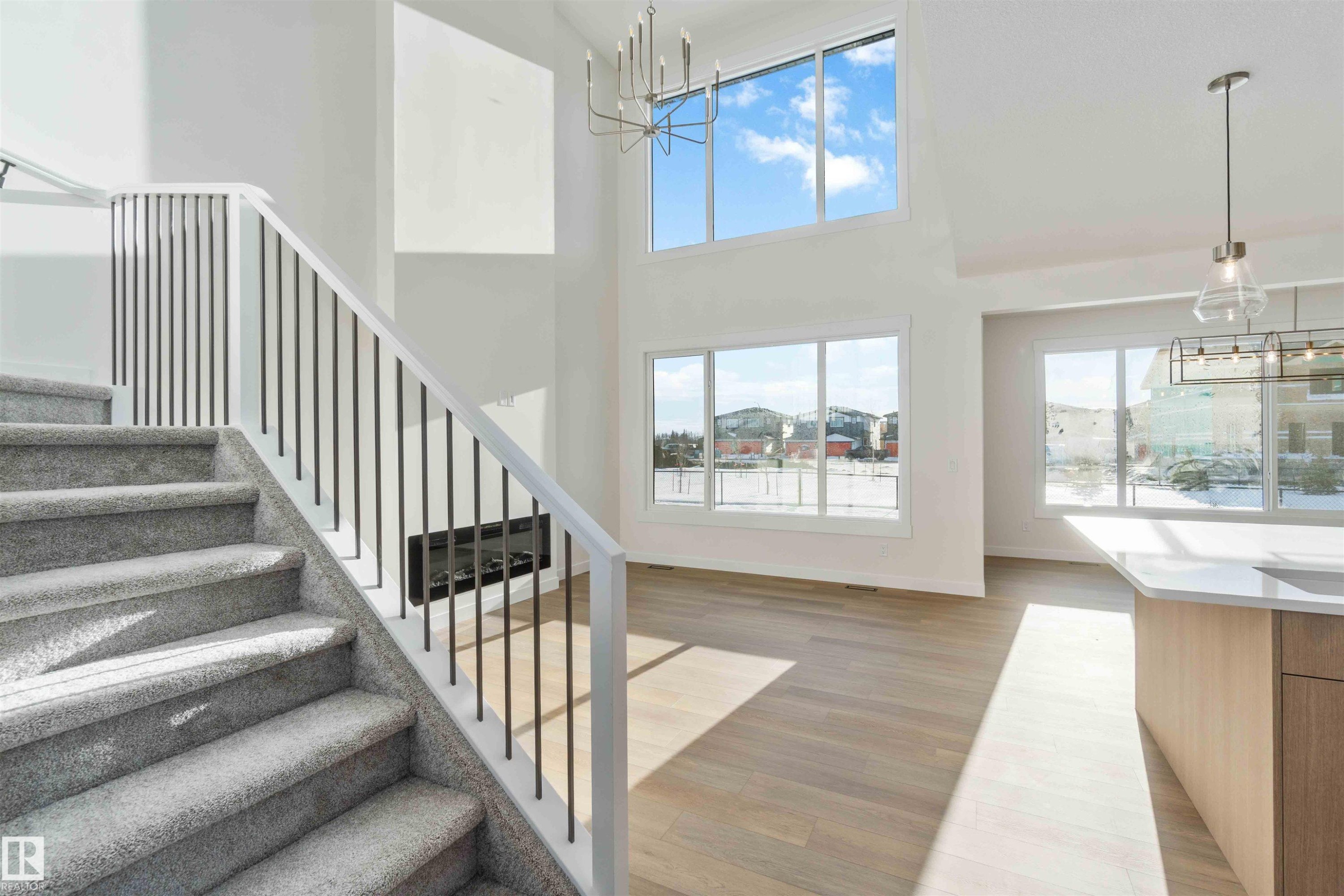 Staircase with a chandelier, plenty of natural light, wood finished floors, and a high ceiling - 2215 4 Avenue, Edmonton, AB - Indoor Photo Showing Other Room