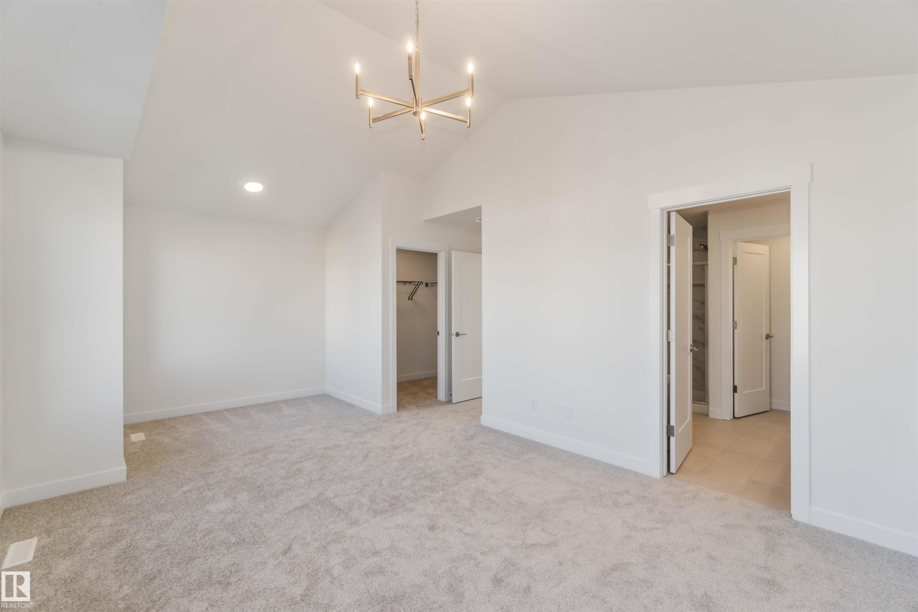 Unfurnished bedroom with a chandelier, light colored carpet, vaulted ceiling, and a walk in closet - 2215 4 Avenue, Edmonton, AB - Indoor Photo Showing Other Room